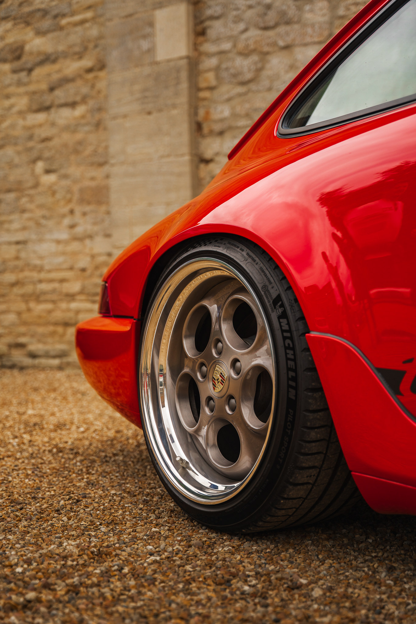 Close-up detail of red Porsche rear wheel and bodywork with shallow depth of field