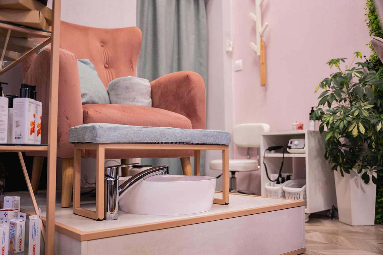 High-end commercial interior photography of a sophisticated nail and pedicure salon. Featuring plush pink chairs, individual foot baths, and a clean, luxury retail aesthetic. Specialist branding imagery by Arcane Media.