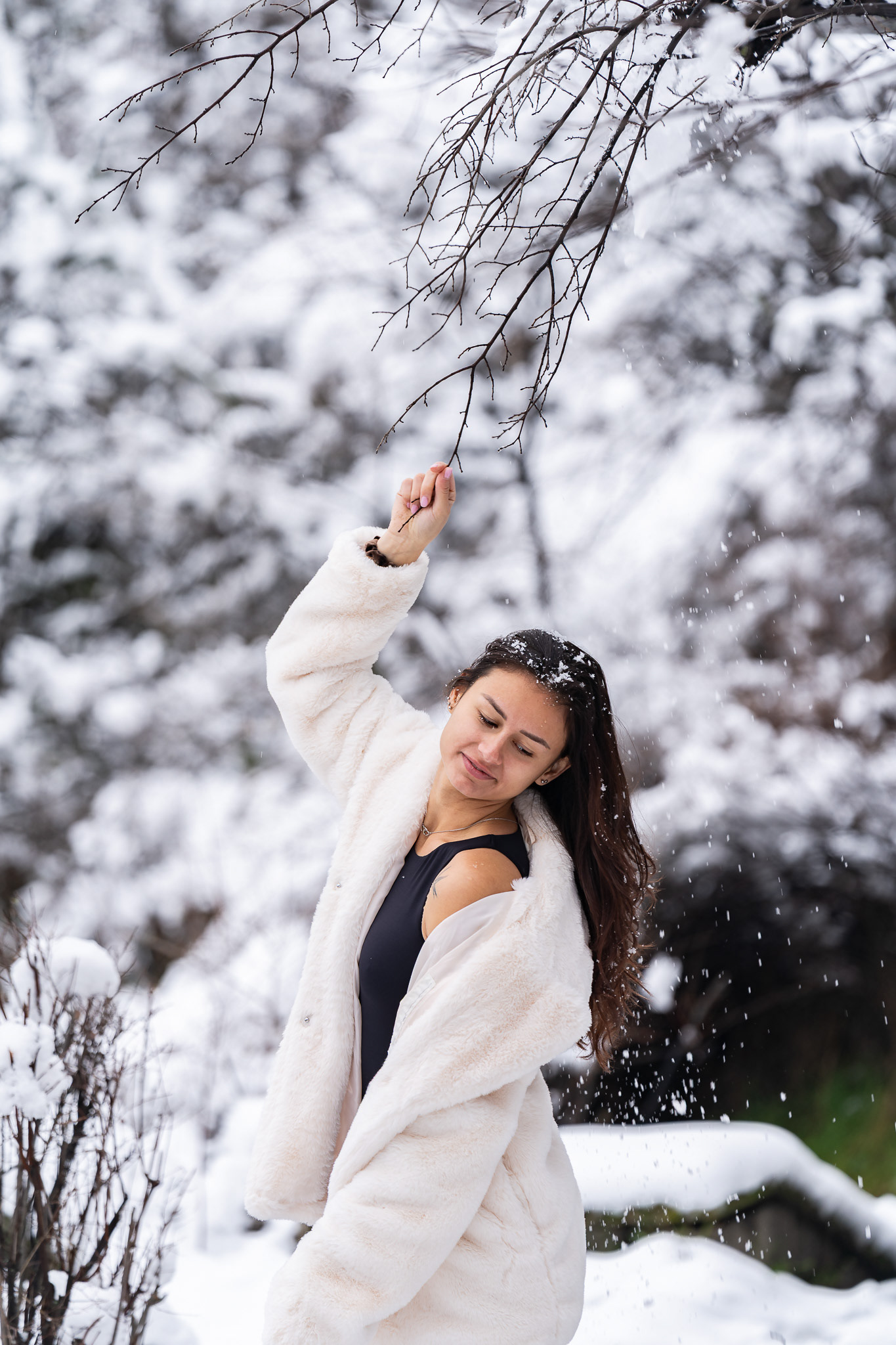 Joyful winter editorial portrait of a female model in a white coat with snowflakes falling. Cinematic outdoor lifestyle photography by Tenyo Barbolski, UK.