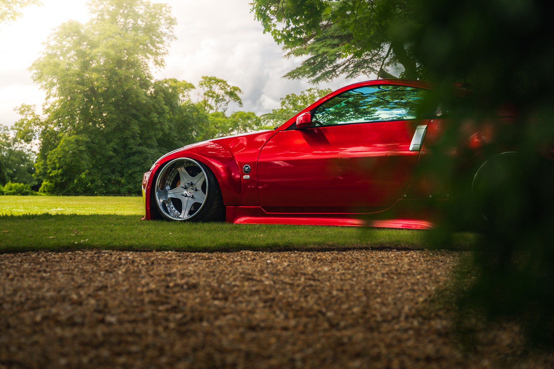 Red Nissan 350z parked on grass with soft natural lighting and clean composition