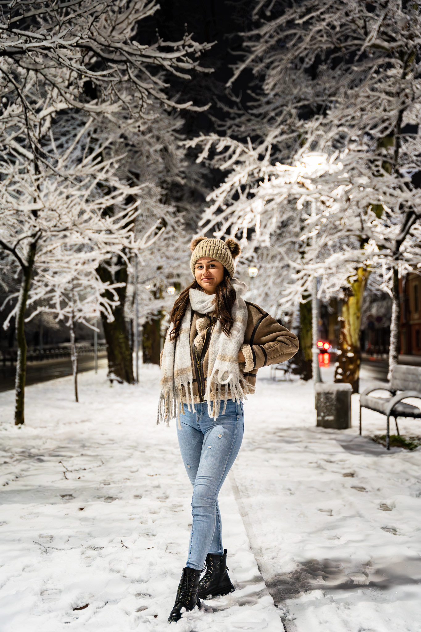 Winter lifestyle portrait of a brunette model in a shearling coat and beanie standing among illuminated frost-covered trees. Photography by Arcane Media.