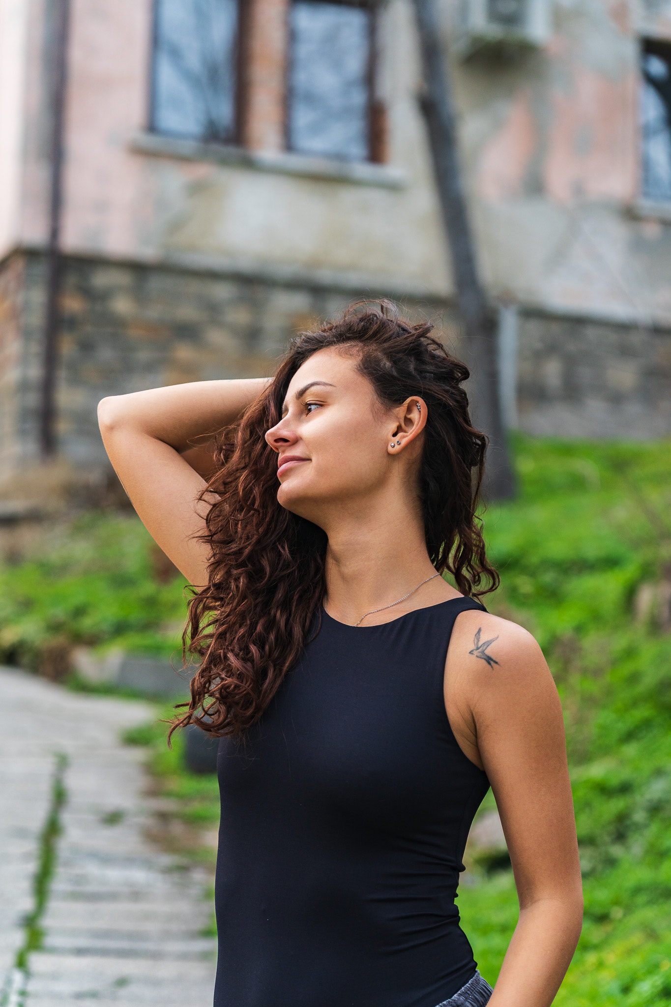 Side profile editorial portrait of a brunette model with curly hair outdoors. Cinematic natural light lifestyle photography by Arcane Media, UK.