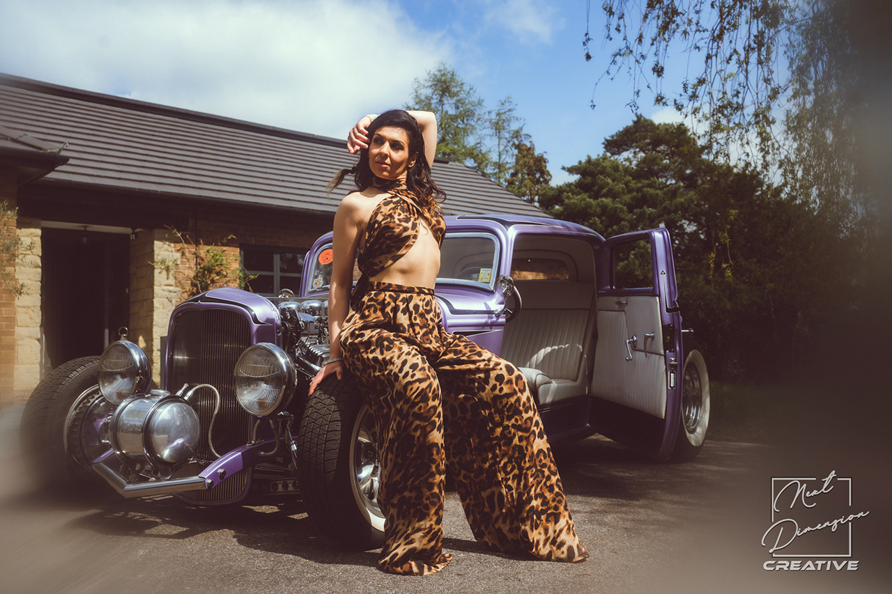Bespoke automotive fashion editorial featuring a model in leopard print with a custom purple vintage Hot Rod. High-end lifestyle imagery for luxury car culture.