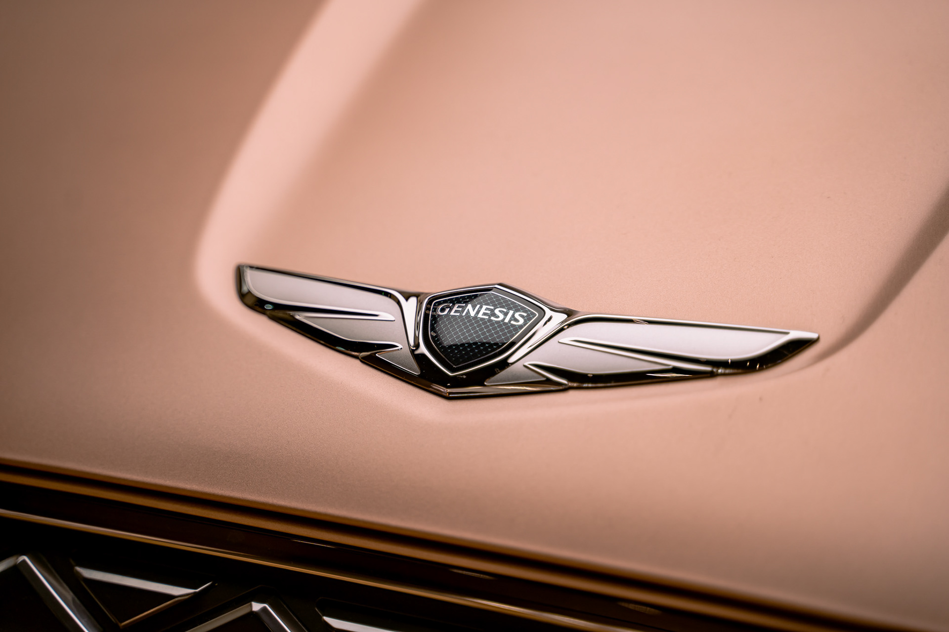 Luxury Genesis wing badge close-up with soft studio lighting