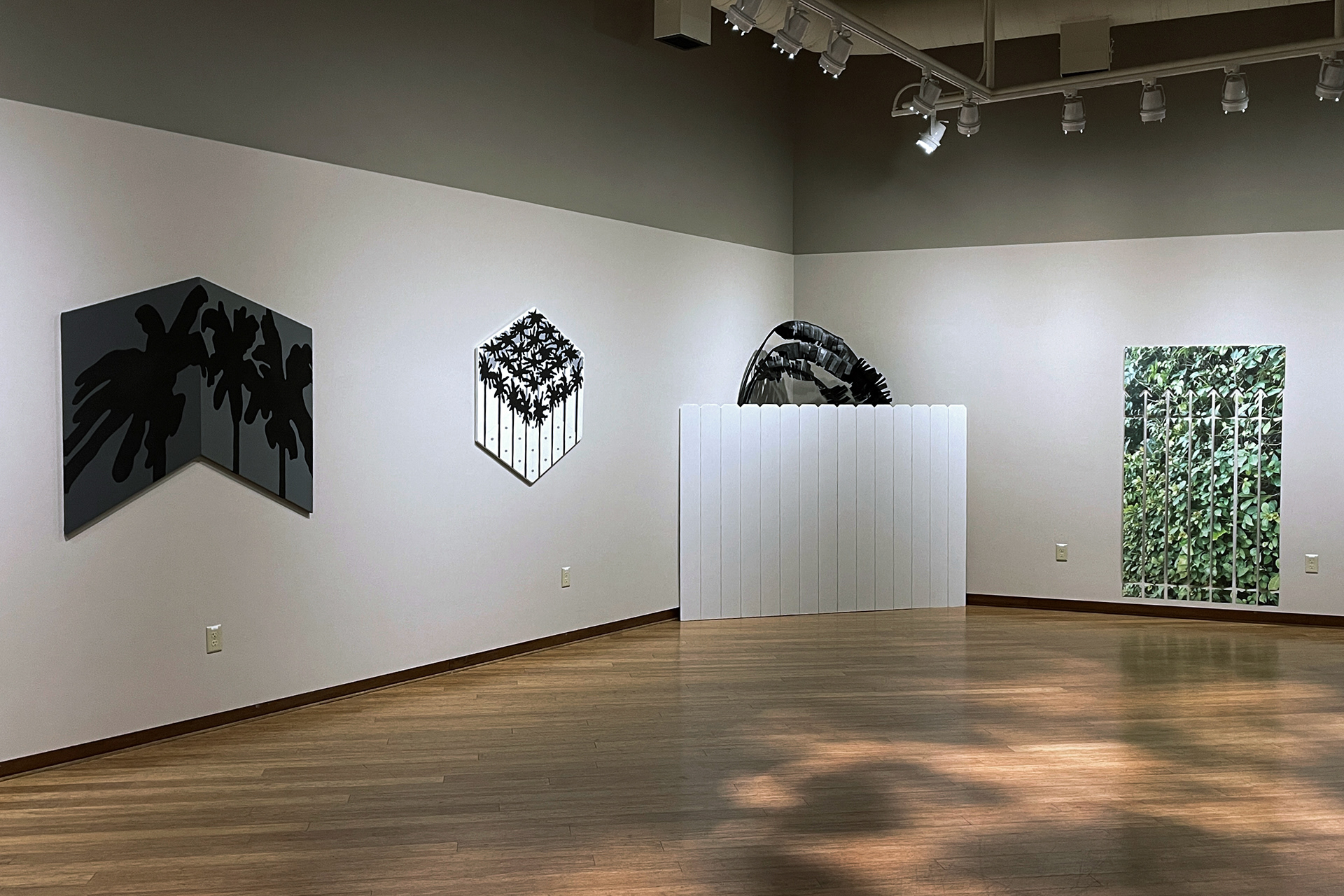 Overview photo of the Walled Gardens exhibition in Roberta's Art Gallery. There are two paintings on the left, and two kinetic paper sculptures on the right.