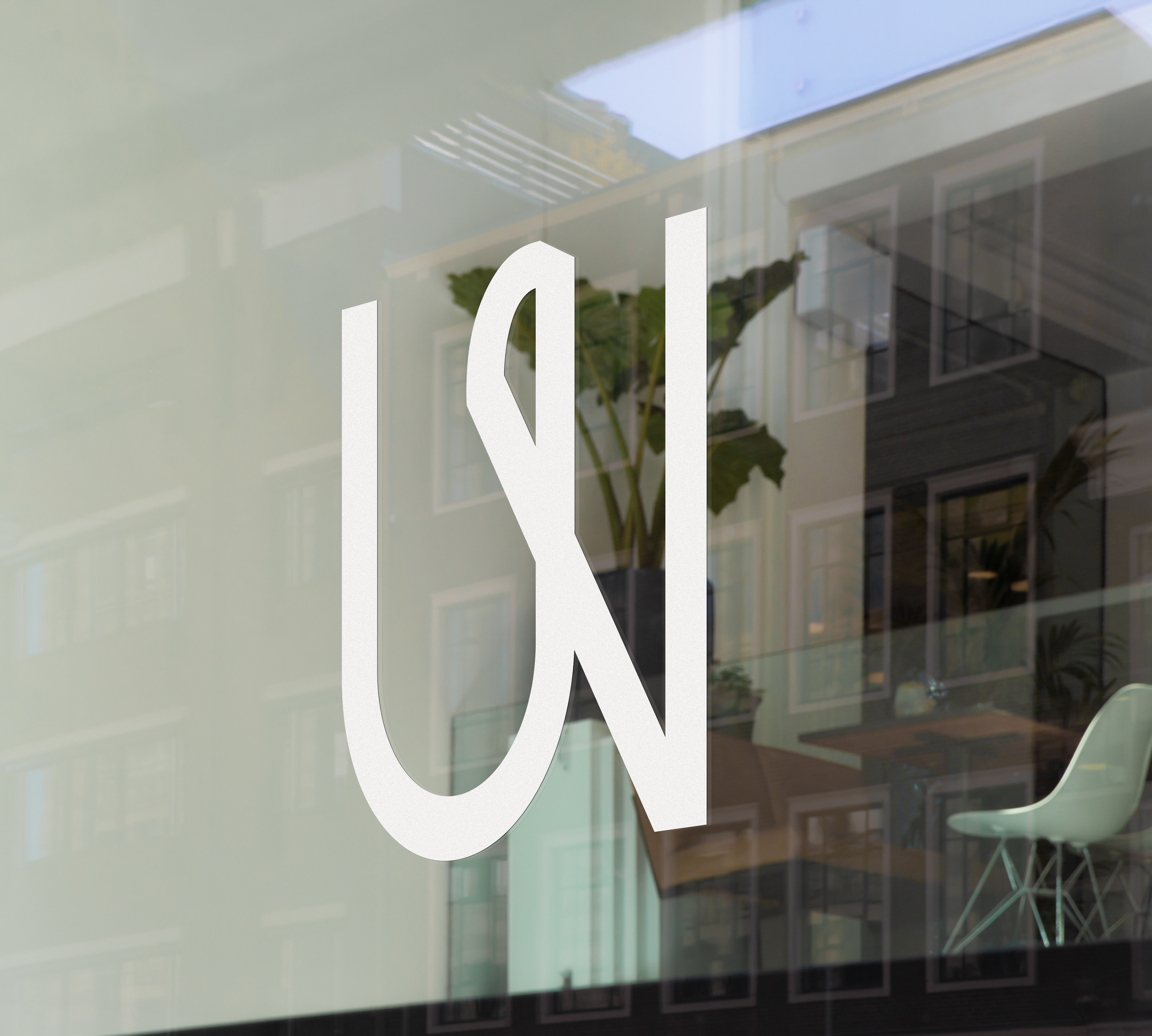 Minimalist office signage for Agentur WIR, featuring the geometric 'WIR' monogram on a sleek architectural surface to emphasize community and collaboration.