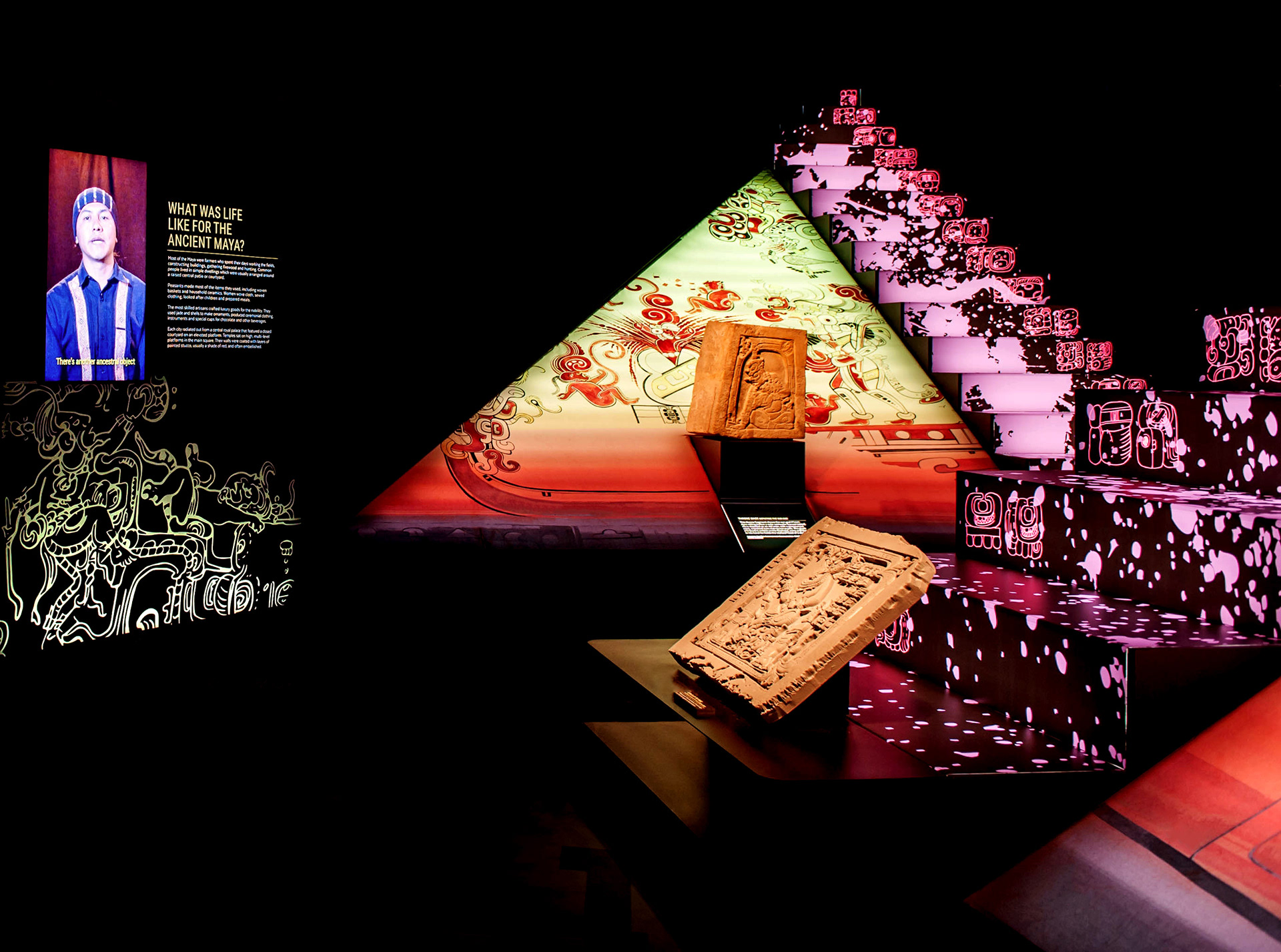 Vibrant backlit fabric exhibition graphics, featuring adapted educational texts and illustrations of Maya imagery to create an immersive museum experience.
