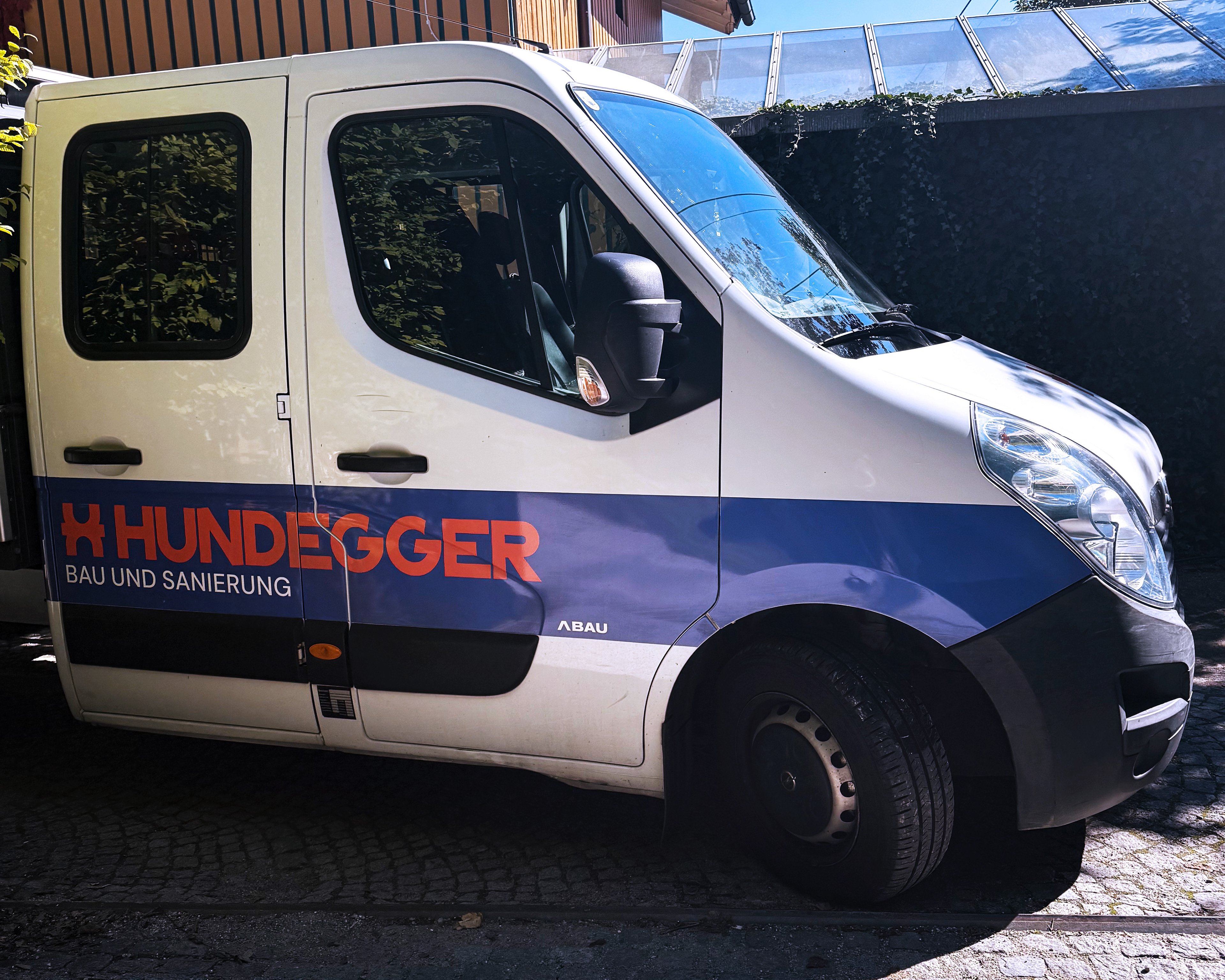 BM-Ing. Hundegger vehicle branding featuring high-contrast navy blue vinyl decals on a white company vehicle for maximum local visibility in Innsbruck.