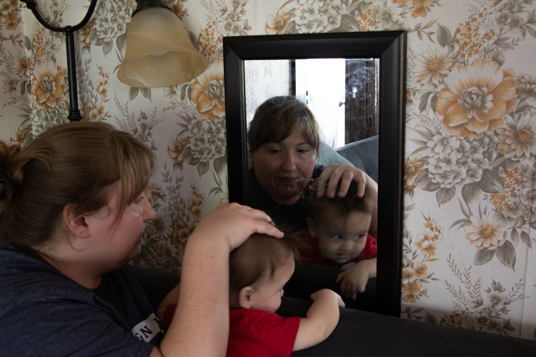Isabelle sits with Hector at a mirror in their living room after dinner.