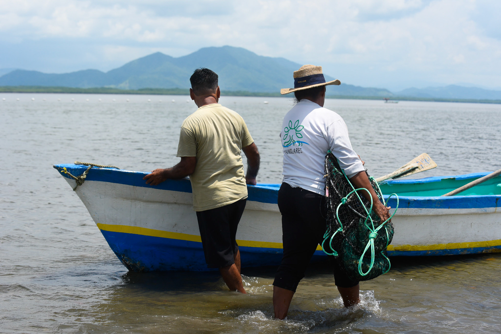 24-junio-2017. Este miércoles 24 de junio visitamos la zona de Puerto Palito en Costa Pajaros, Puntarenas. Desde los años 80, Doña Siday Arias, en conjunto con la Universidad Nacional, han dedicado tiempo para evaluar las posibilidades del cultivo de las Ostras en el Golfo de Nicoya. Hoy día cuentan con 6 granjas. En Puerto Palito, nos encontramos con un grupo de trabajadores que se encargaban cada uno de su tarea: limpieza, selección de Ostras por tamaño, llevar nuevamente al mar, a las que no cumplían con el tamaño mínimo para la comercialización (6cm), entre otras labores. Fotos: Nina Cordero. En la Fotografía: Eugenia Fernandez,  se encaminaba a la lancha para devolver al mar la Linterna con las Ostras que no cumplían el tamaño de los 6 cm para la comercialización, junto a Gregorio Matarrita.