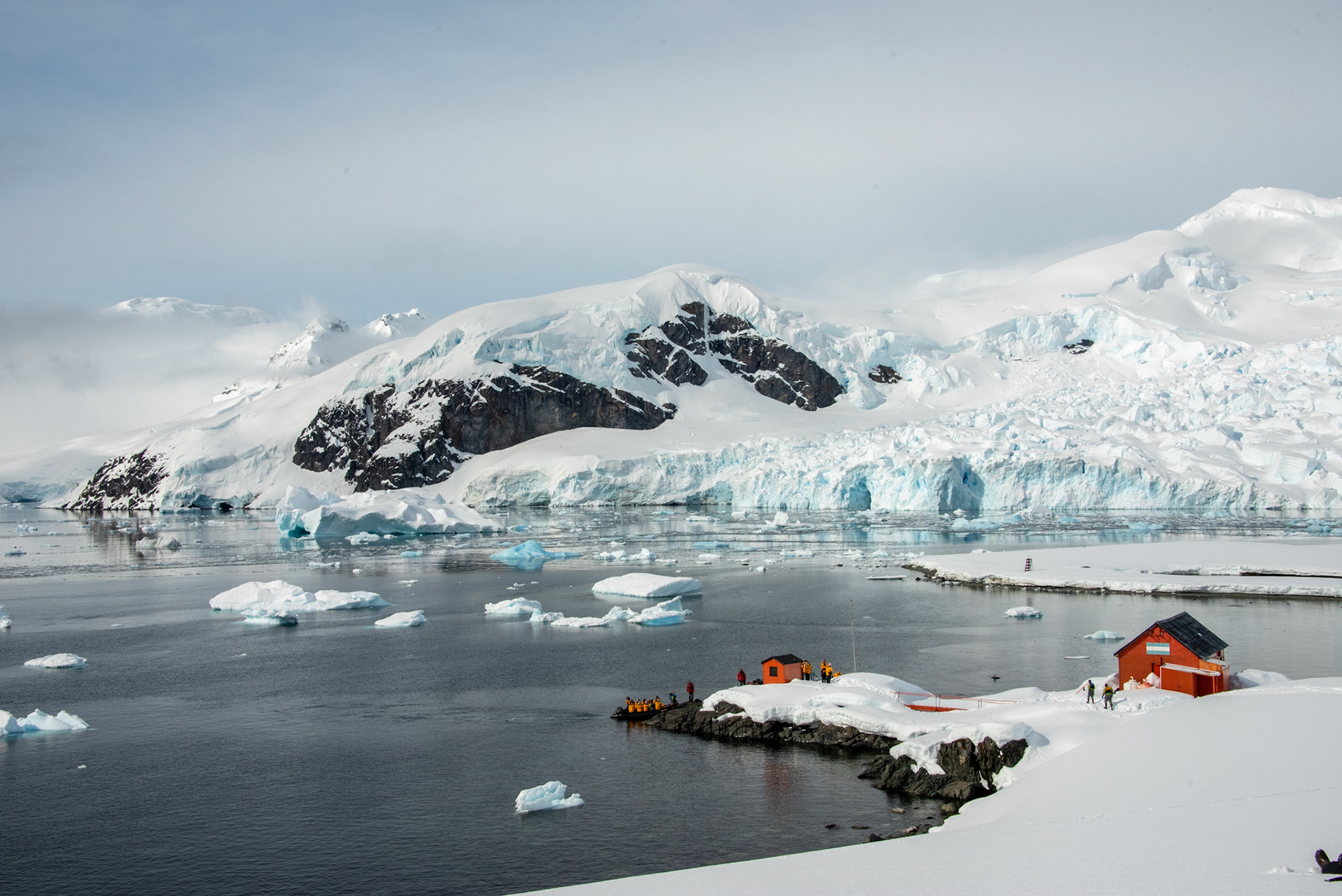 Antarctica. A small landing point beneath a vast wall of ice..