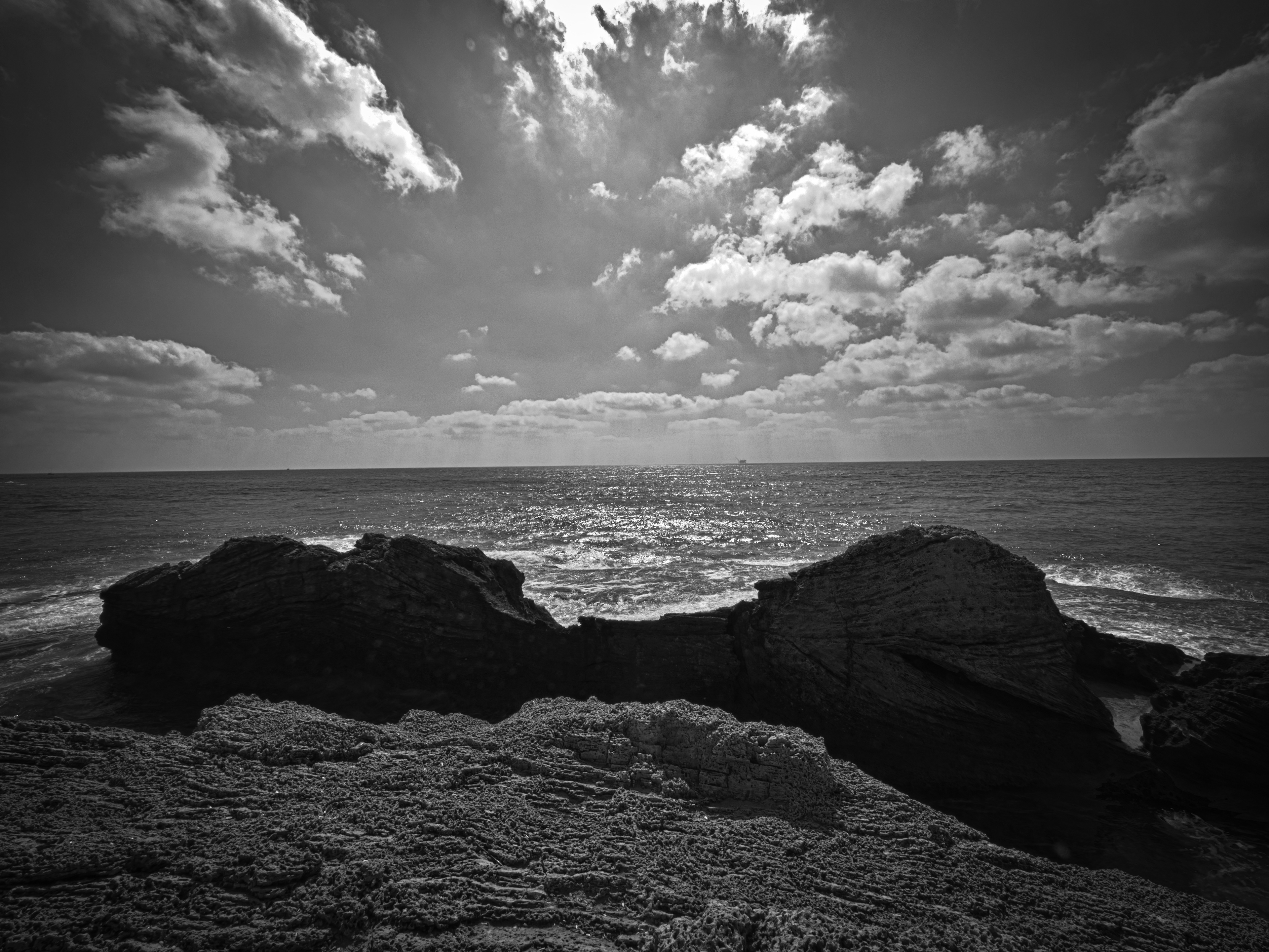 Black and white photo of the rocks and a small pool in the sea