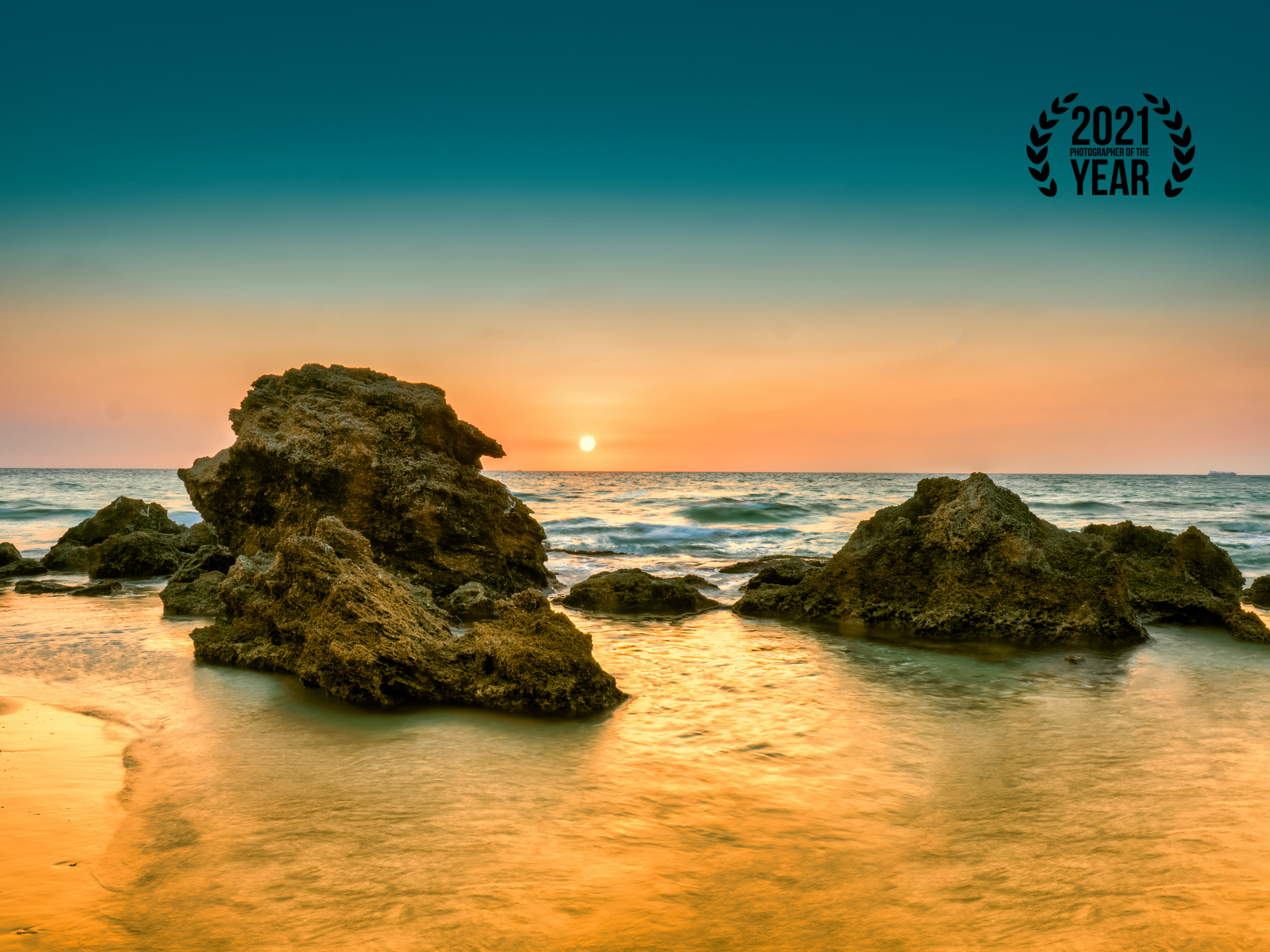 Sunset in dor beach facing the sun with rocks in the foreground and the sea in the middle-ground and the clerar skiy and sun in the background