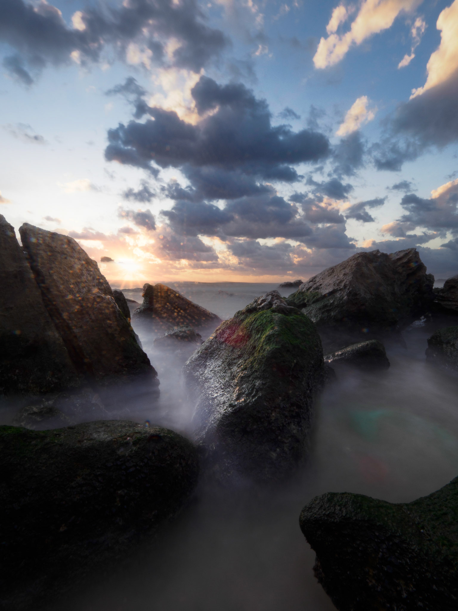 Golden hour seascape with warm sunlight breaking through clouds