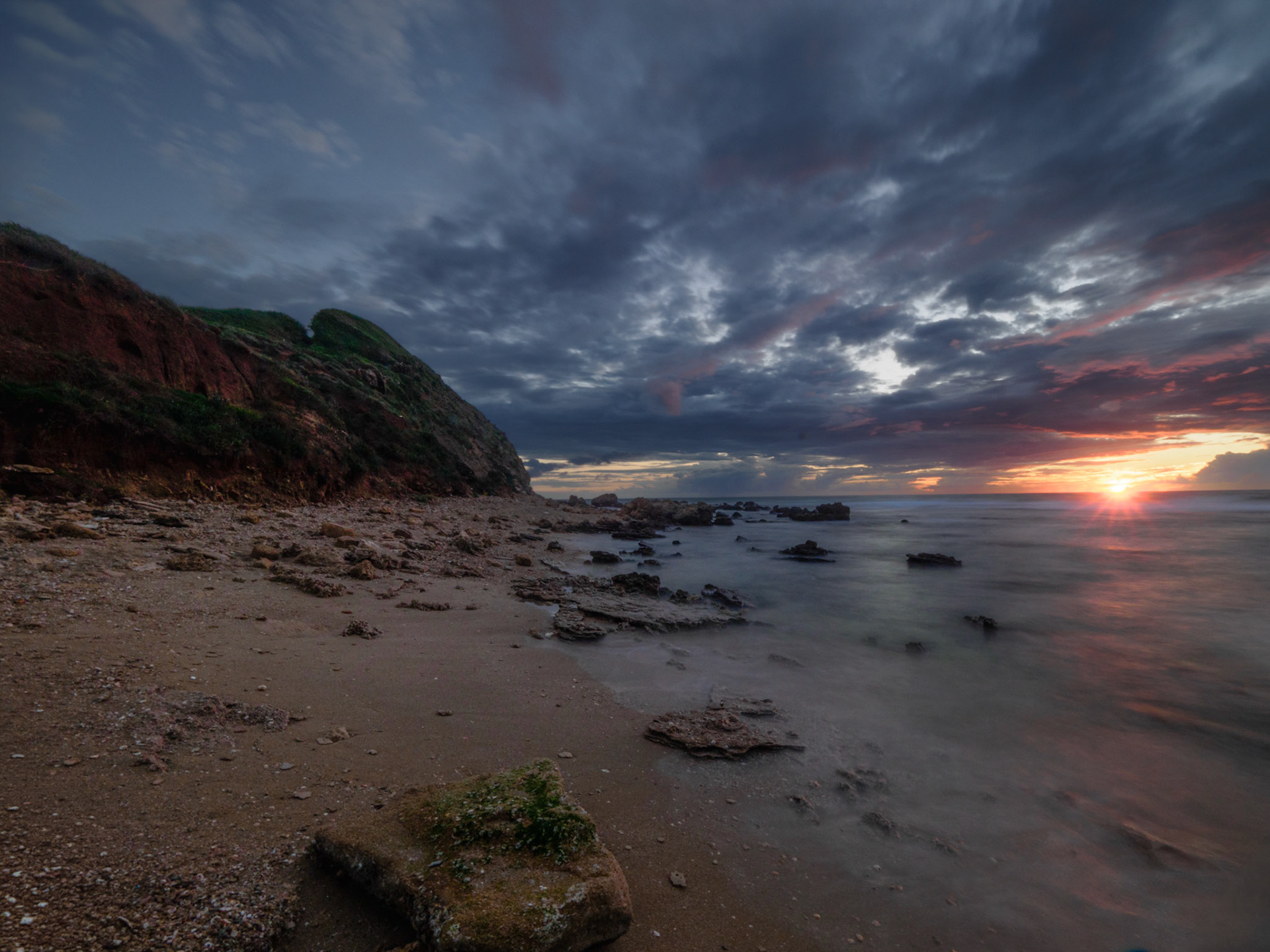 Mediterranean seascape at golden hour with dramatic clouds and wet rocks
