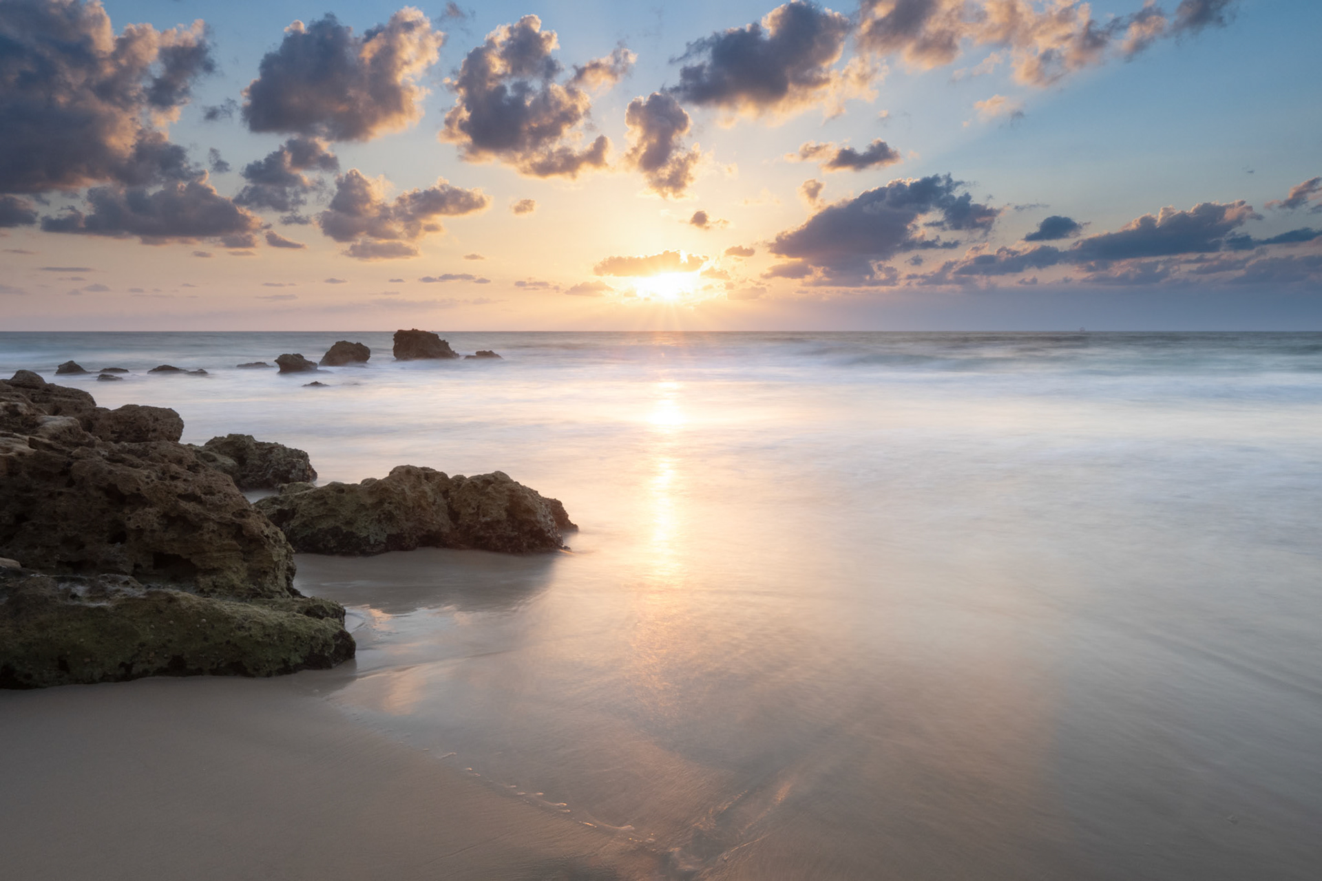 Color photo of some rocks and the beach during the sunset