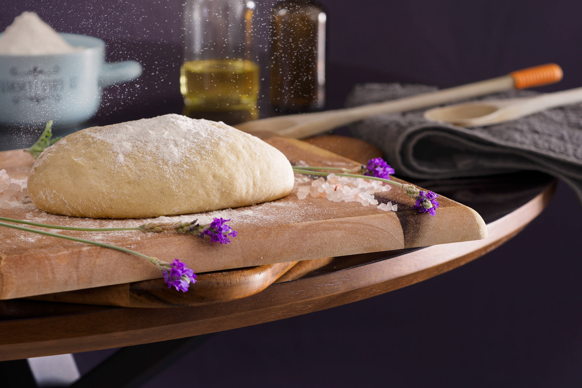 Dough is kneaded on a wooden surface with flour sprinkled on top