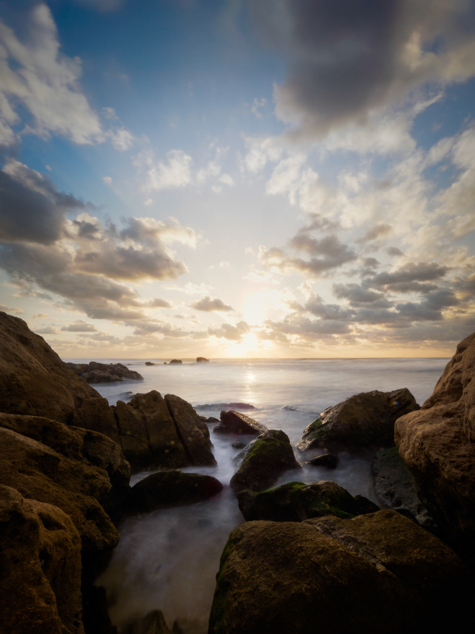 Golden light illuminating wet coastal rocks in a Mediterranean seascape