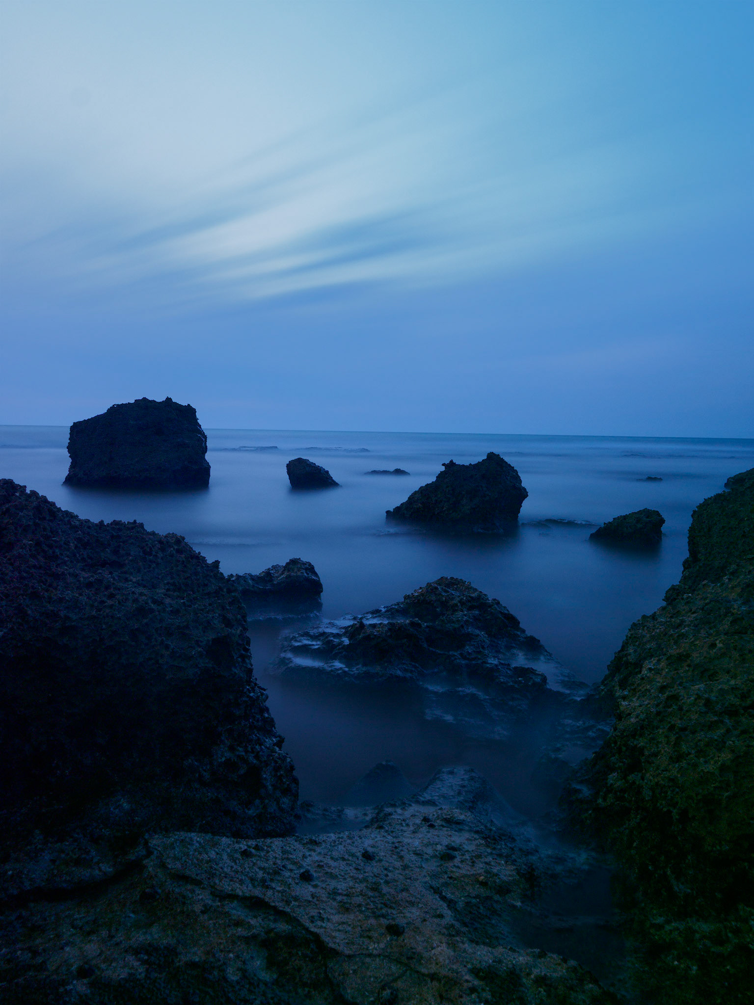 Long exposure blue hour seascape with deep blue tones and soft waves