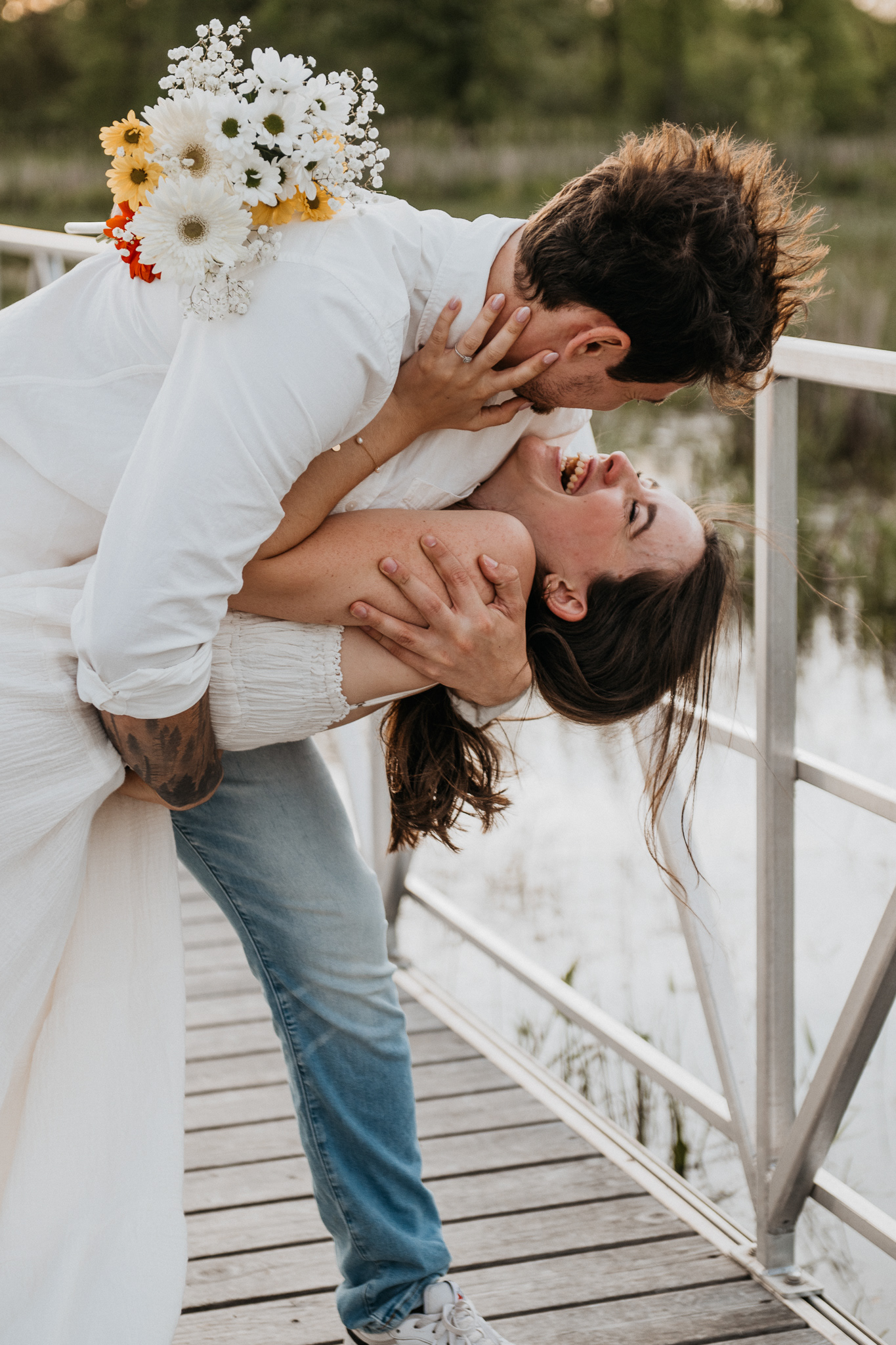 couple laughing after a dip kiss, engagement session, girl holding flowers