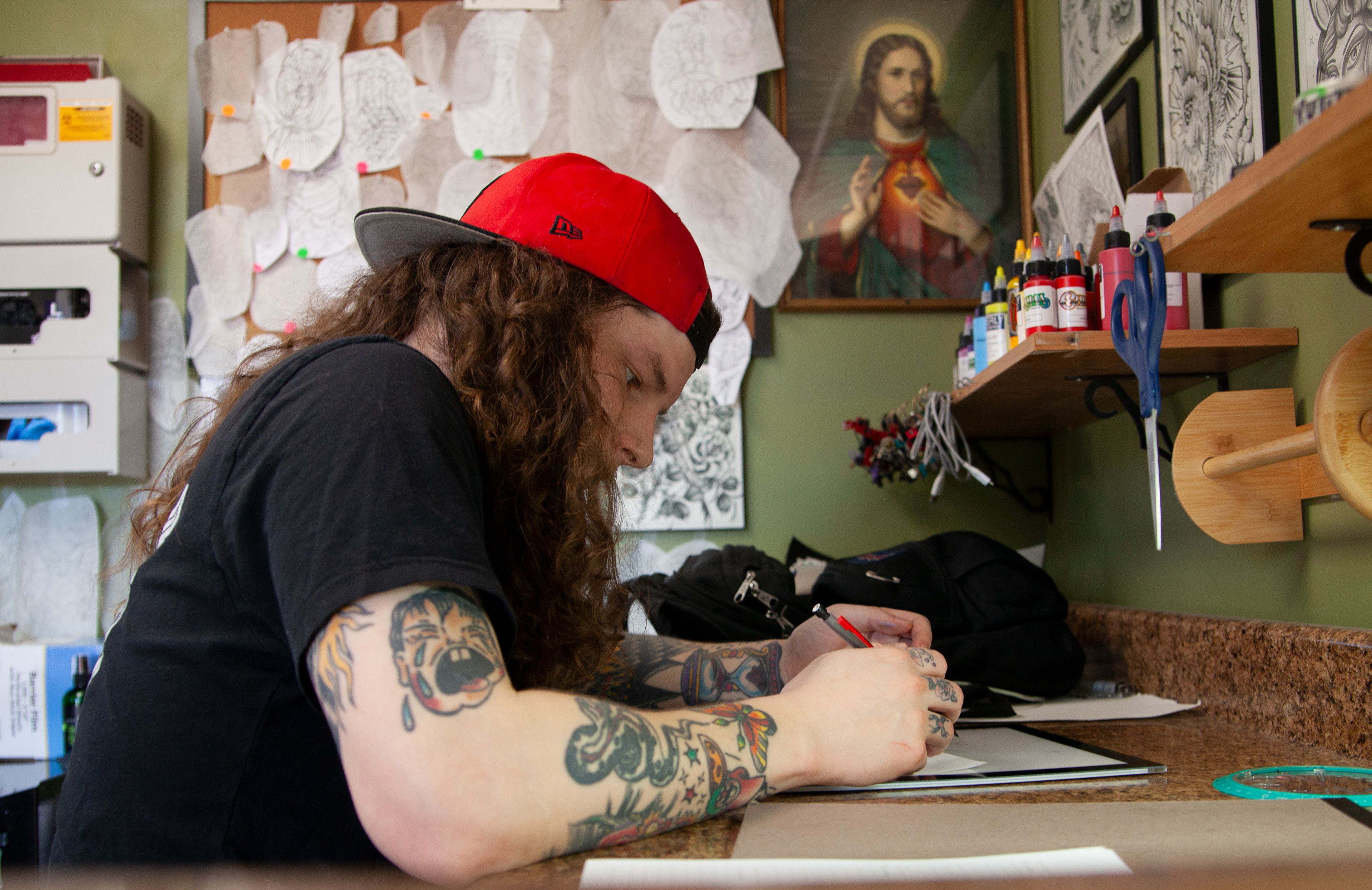 Michael Harris, a tattoo artist at Magic Tattoo on Stimson Avenue, drawing on a piece of paper during his downtime at work, Feb. 14, 2024 in Athens, Ohio. Harris is having a slow Wednesday afternoon and is awaiting Valentine's day plans with his wife. 