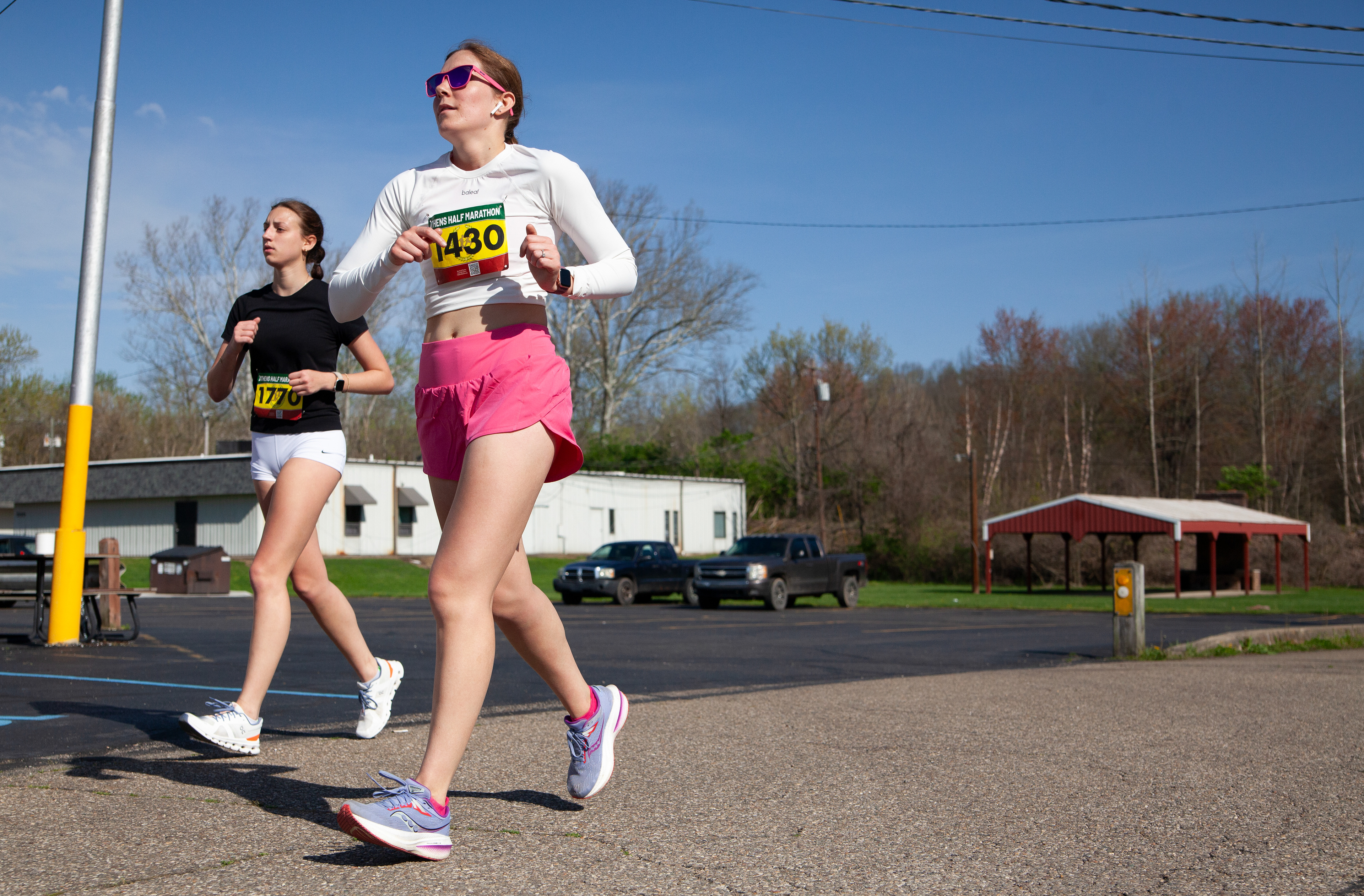Allison Tarone (right) and Abby Motter (left) run to cross Union Street toward the end of the Athens half marathon, April 14, 2024, in Athens.