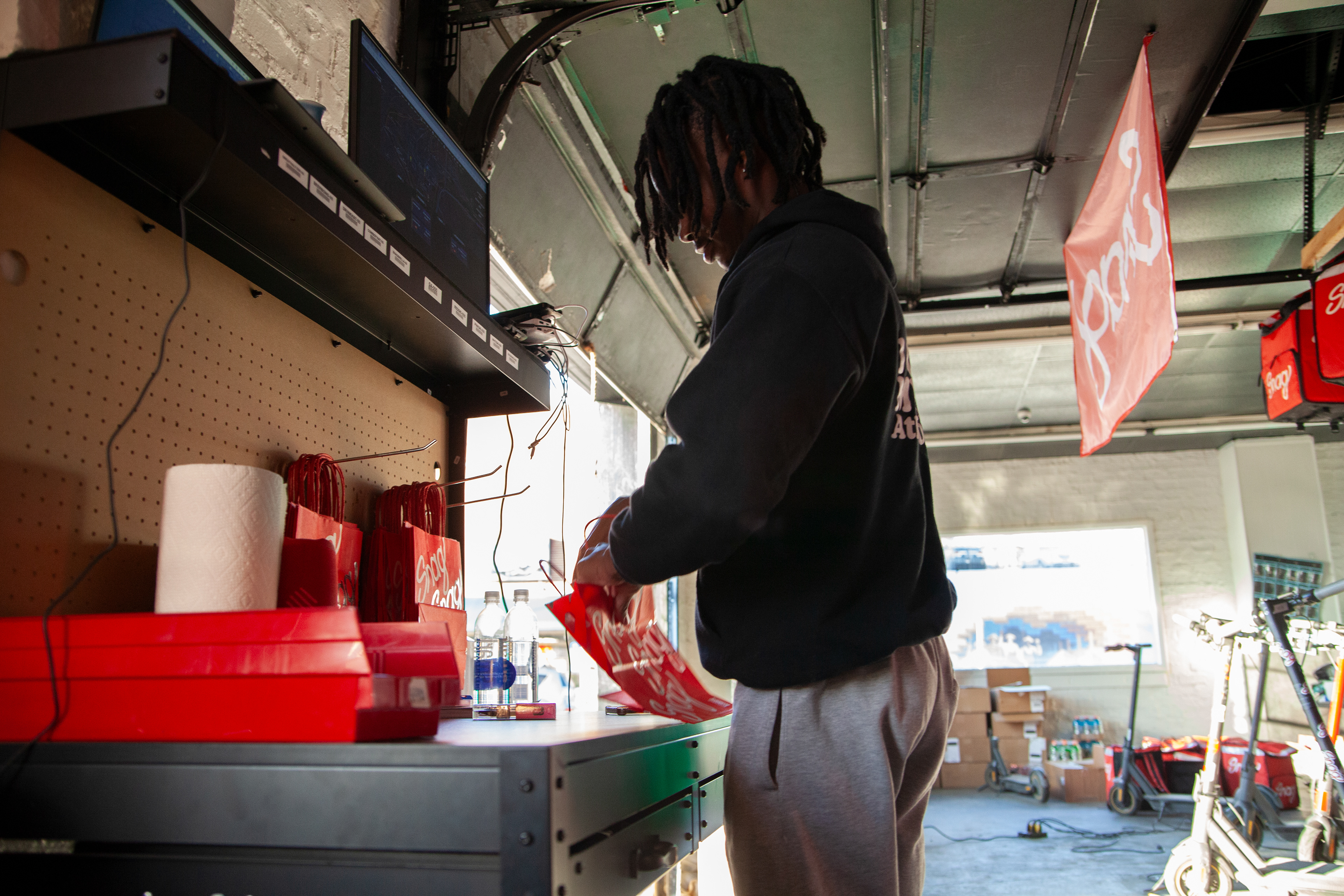 Snag employee, Jaedon Thomas, prepares an order for delivery in the Athens Snag warehouse located on Stimson Avenue, Feb. 20, 2024 in Athens, Ohio. Snag is a delivery service on various college campuses with the appeal that it delivers groceries, drinks and other household items quickly on scooters. 