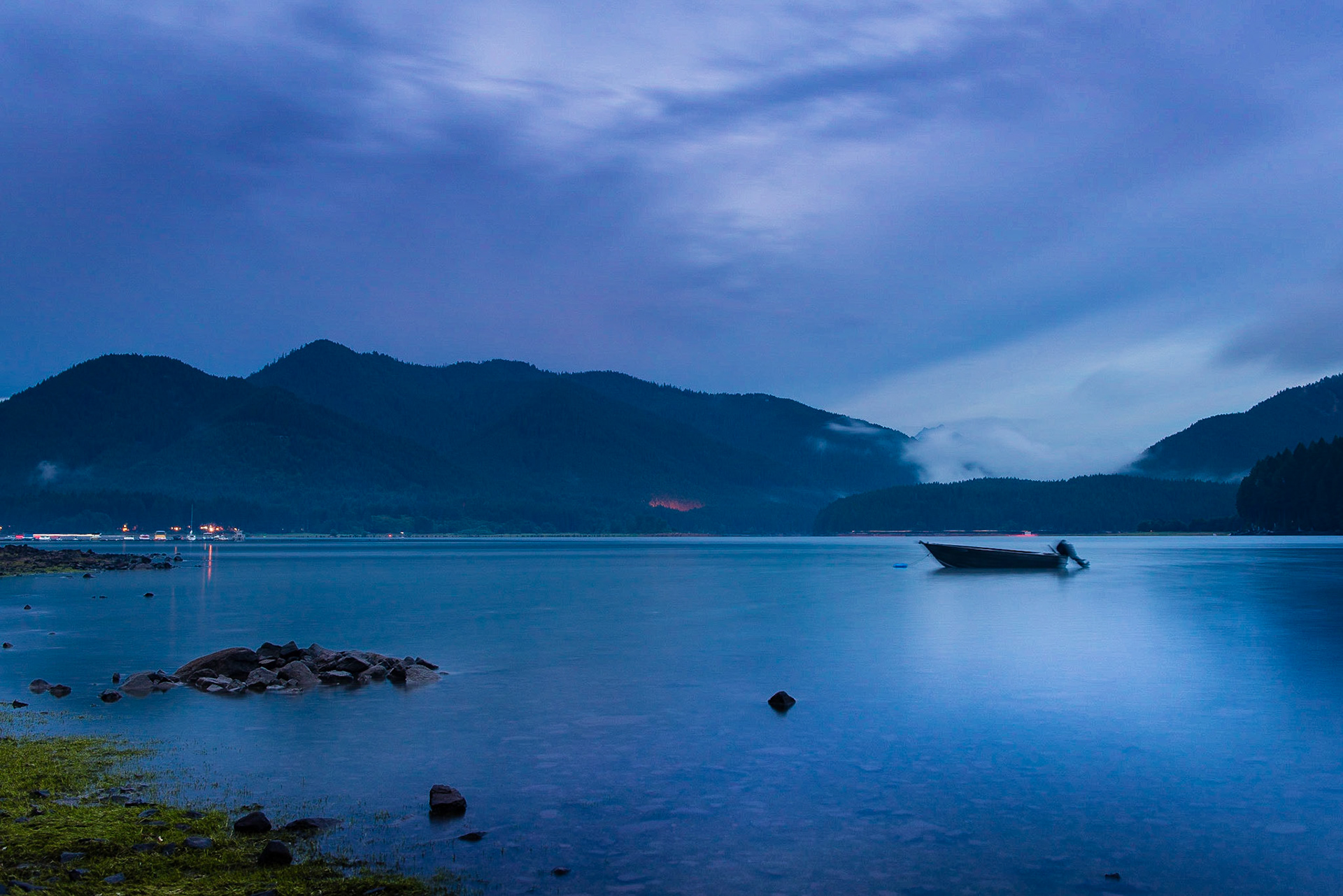 A fishing boat anchored for the night at a lightning storm rolls in over Detroit Lake, Oregon.
