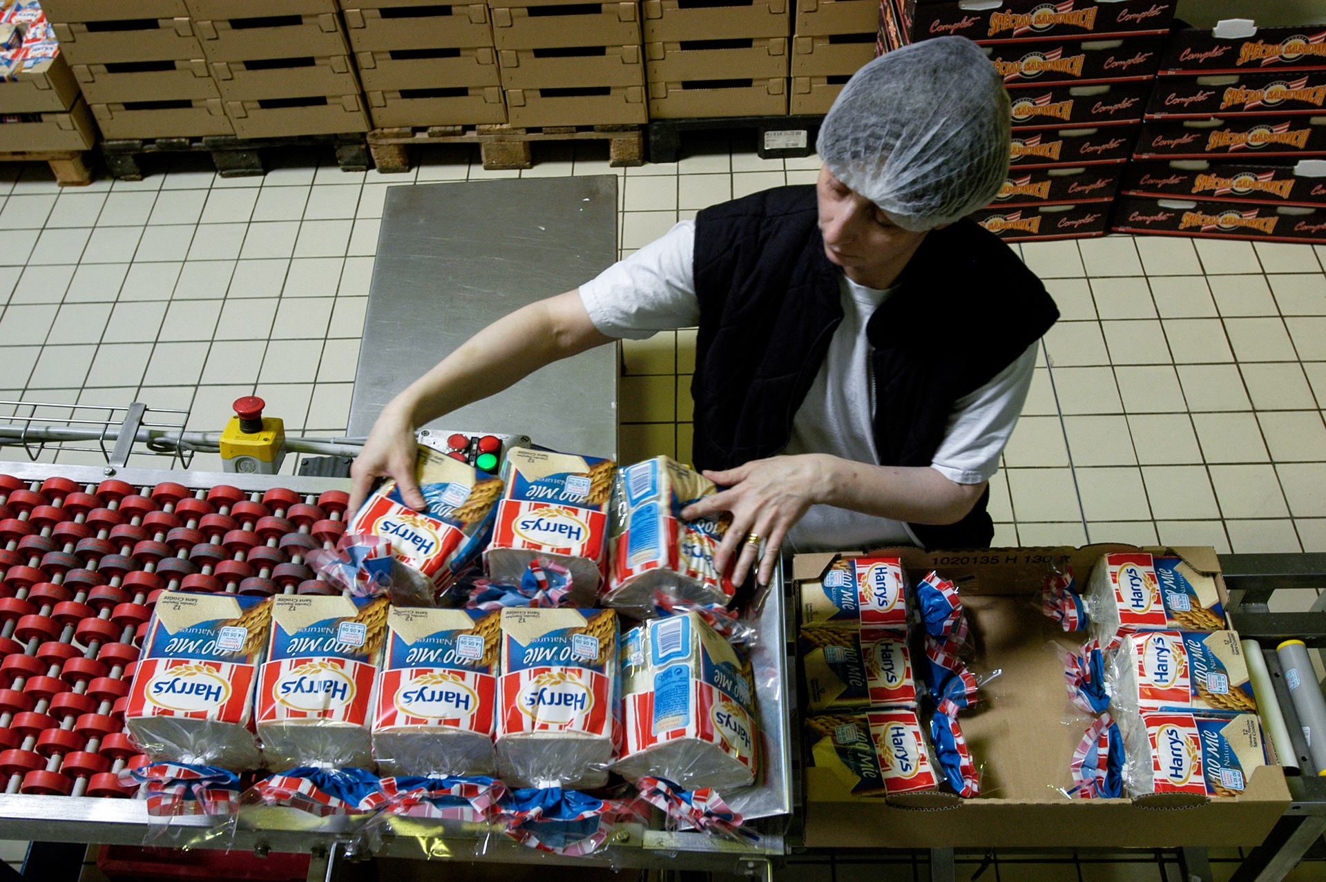 An employee boxes prepackaged American style sandwich bread on the production line at Harry's original factory in Châteauroux.