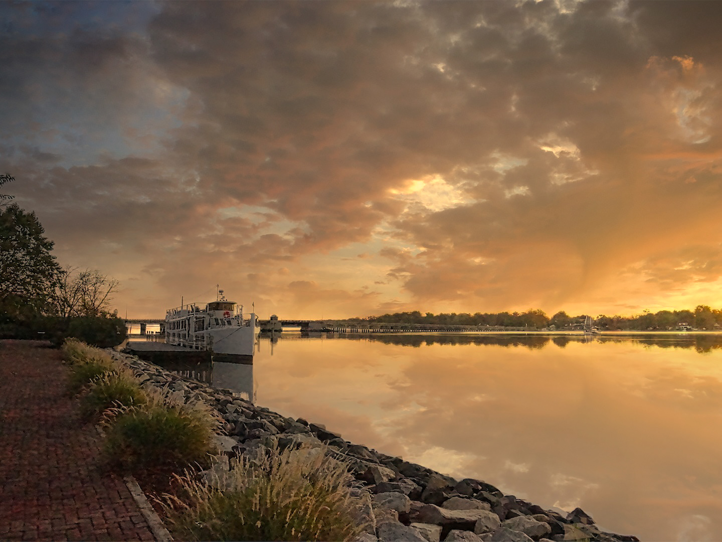 Scenic sunrise with a boat anchored on a peaceful river.