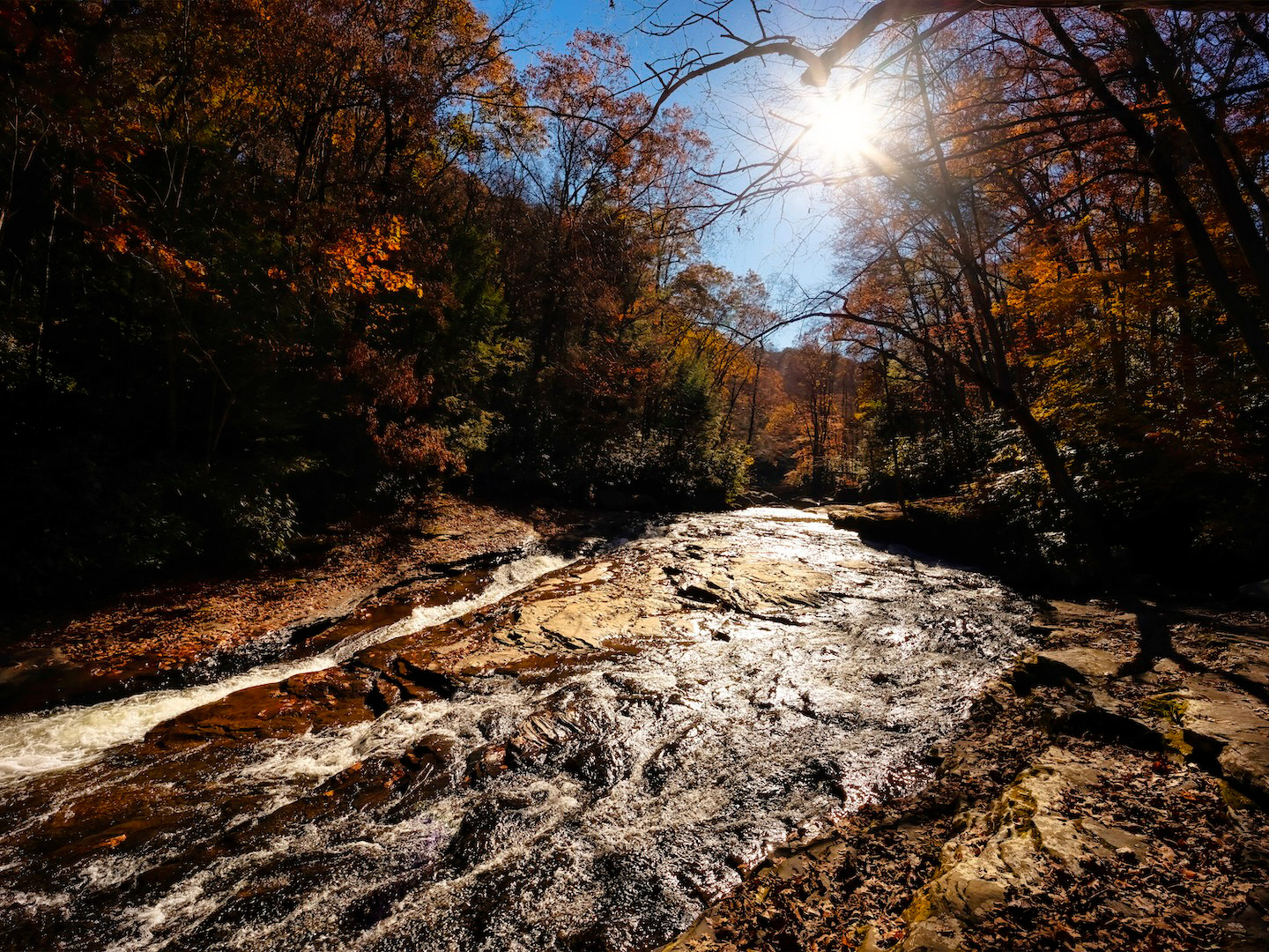 The Meadow Run stream winds its way through large slabs of stone and colorful Fall foliage in Ohiopyle, Pennsylvania.