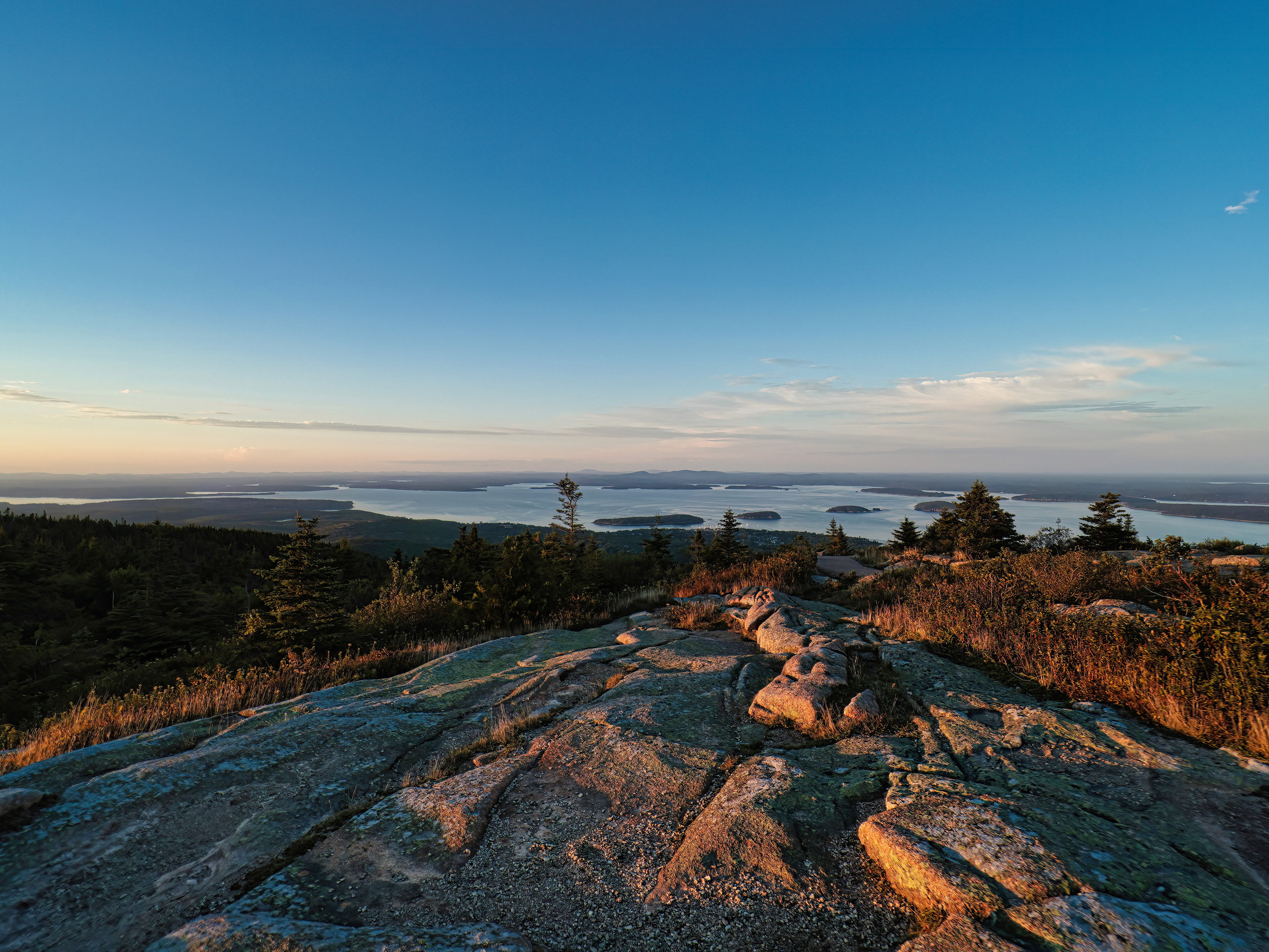 A clearing sunset viewed from the summit of Cadillac Mountain in Acadia National Park, Maine, showcasing colorful skies and panoramic views over the park.