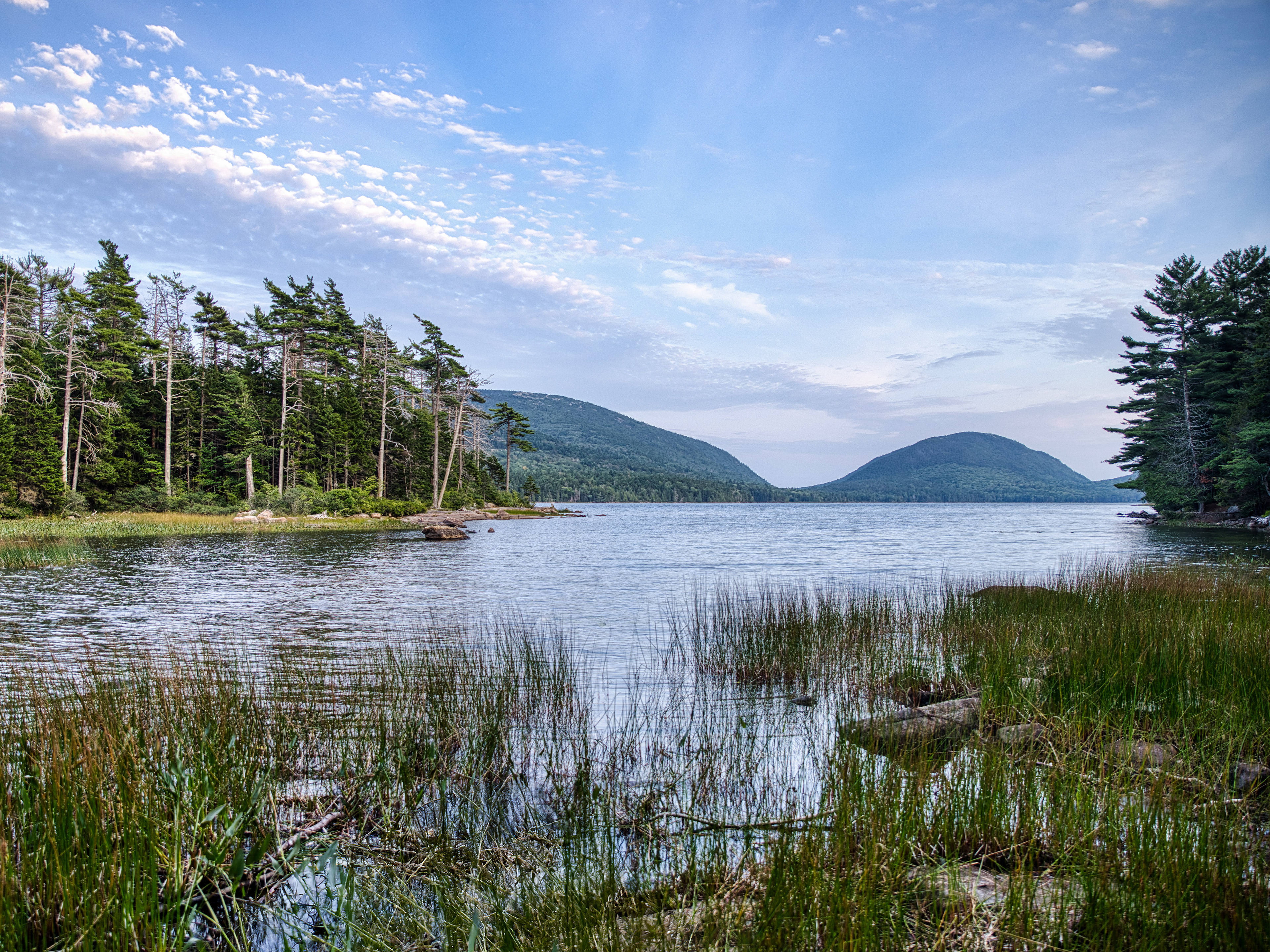 View of Eagle Lake in Acadia National Park, Maine, during the early evening, with the water reflecting the fading light and surrounding landscape.