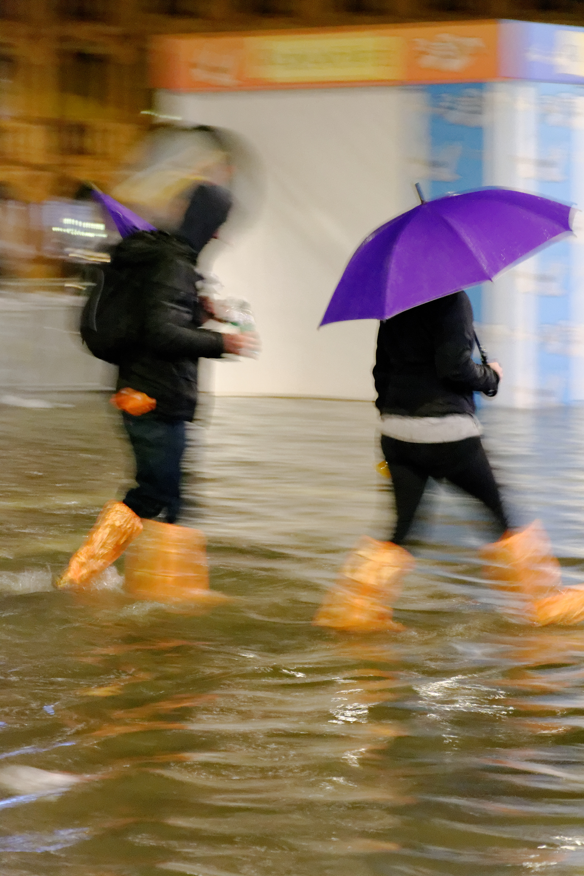 Touristes en bottes oranges avec parapluie violet, sur la place Saint Marc