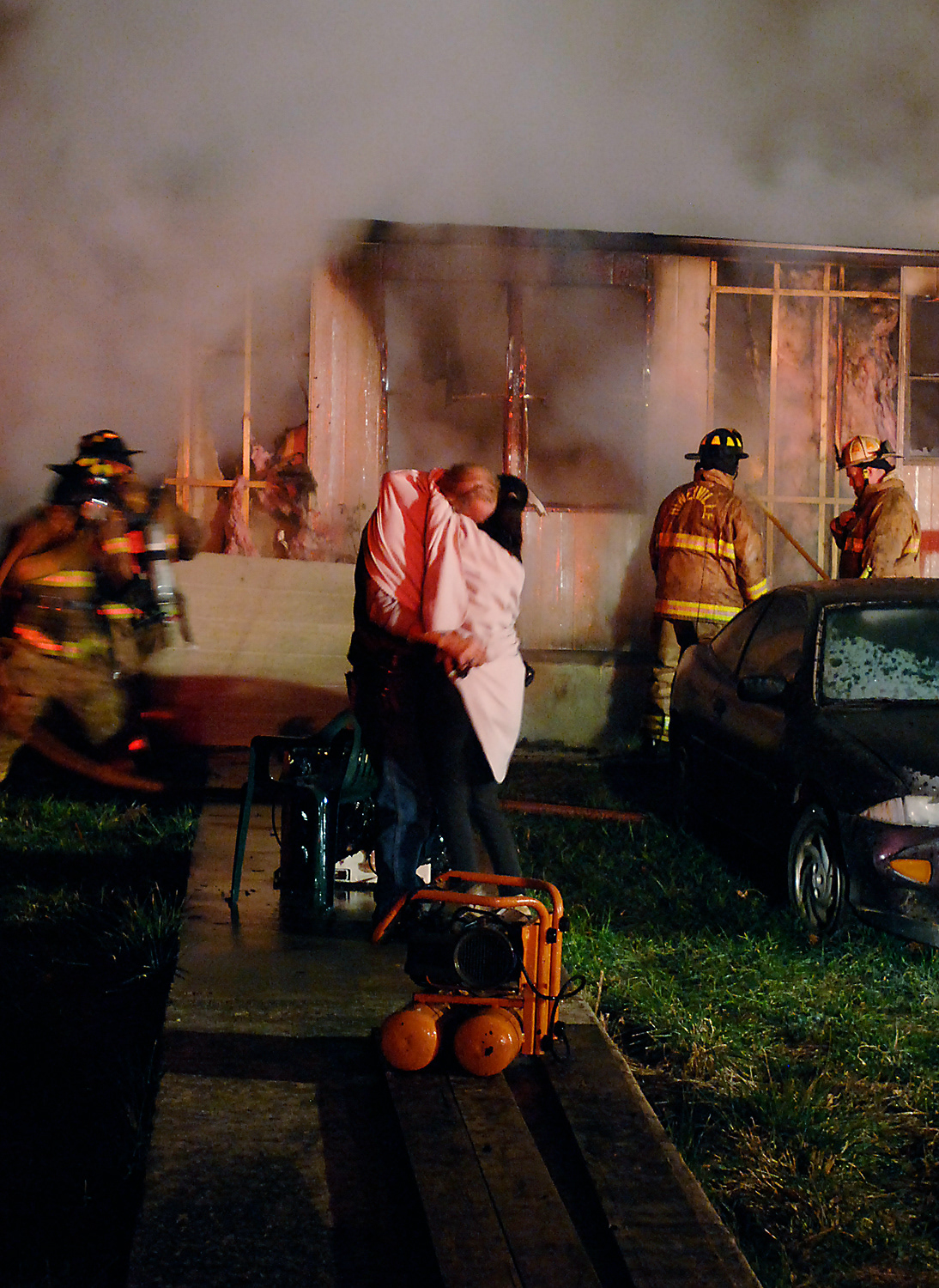 A woman comforts the homeowner of the residence burning in the background Wednesday, Nov. 28, 2012, in the Rineyville, Kentucky, area. (Jill Pickett/The News-Enterprise)