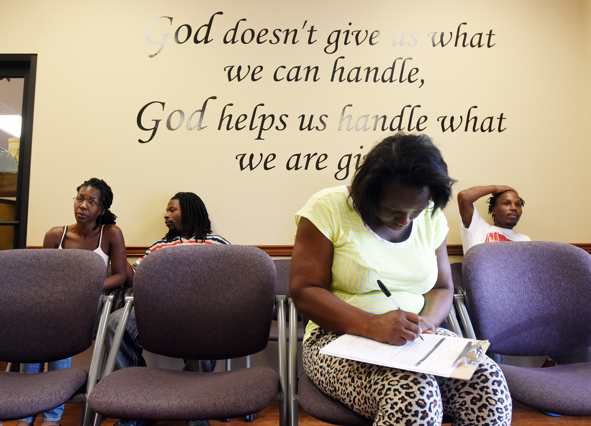 Equanika Noel fills out paperwork for her family and others staying at her sister's house in Rineyville, Kentucky, as her husband, Brandon, right, and Dondreeca Smith and Nathaniel Bartley, two of the several staying at the house, wait Friday, Aug. 19, 2016, at Helping Hand of Hope in Elizabethtown, Kentucky. They fled Louisiana after having to leave their homes because of flooding. Her sister had moved a couple months ago to Hawaii and offered the house in Rineyville to them for shelter. (Jill Pickett/The News-Enterprise)