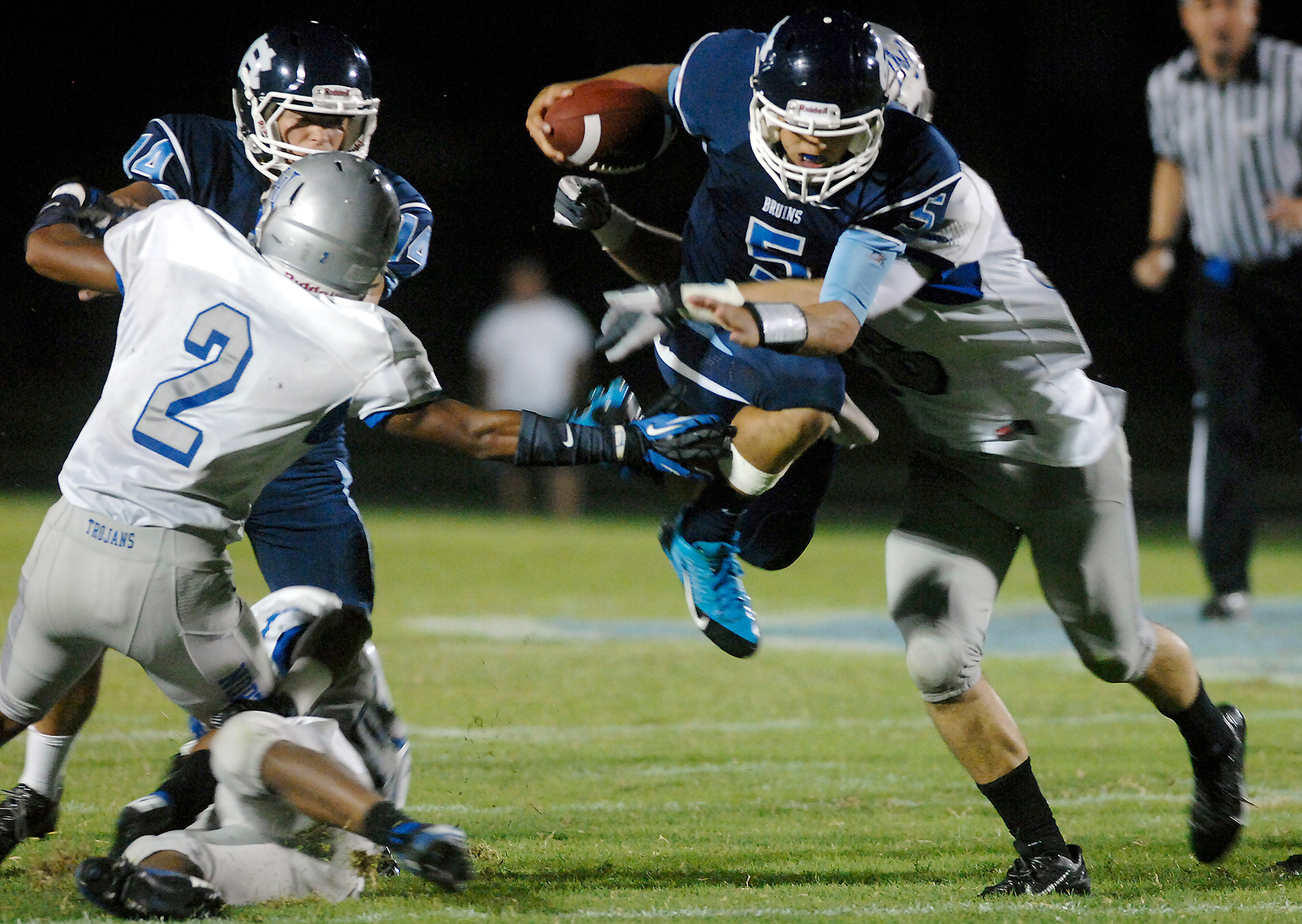 Central Hardin's Koree Krupinski leaps to avoid one North Hardin tackler as another, North Hardin's Cameron Savage wraps him up during varsity action Friday, Aug. 23, 2013, at Central Hardin High School. (Jill PIckett/The News-Enterprise)