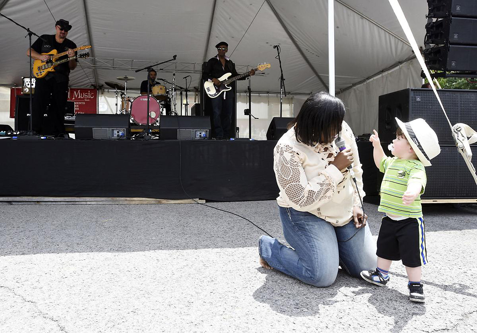 Anji Brooks sings to Braxton England, 23-months, as her Top Dollar Blues Bland plays in the background Saturday, May 27, 2017, during BBQ, Blues & Bikes in downtown Elizabethtown, Kentucky. Brooks spotted Braxton dancing and asked him to be brought to the stage. (Jill Pickett/The News-Enterprise)