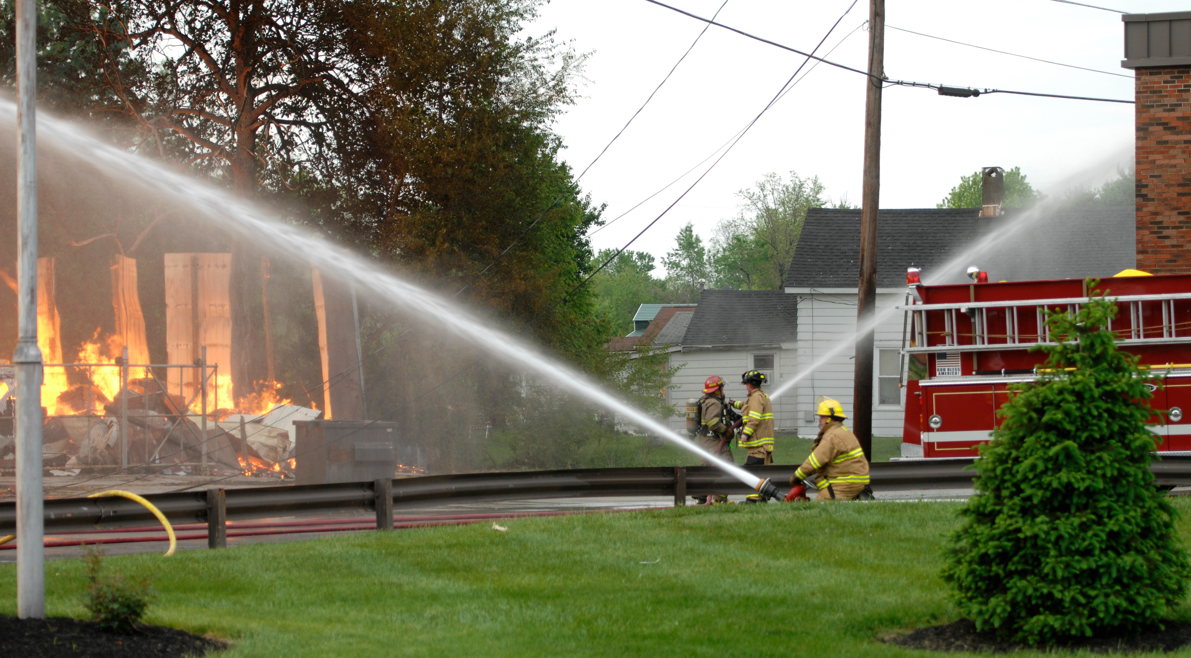 A firefighter aims a hose onto the fire destroying the Lord Company building as another firefighter sprays water to cool The Cecilian Bank across the street Saturday, May 9, 2015, in Cecilia, Kentucky. (Jill Pickett/The News-Enterprise)