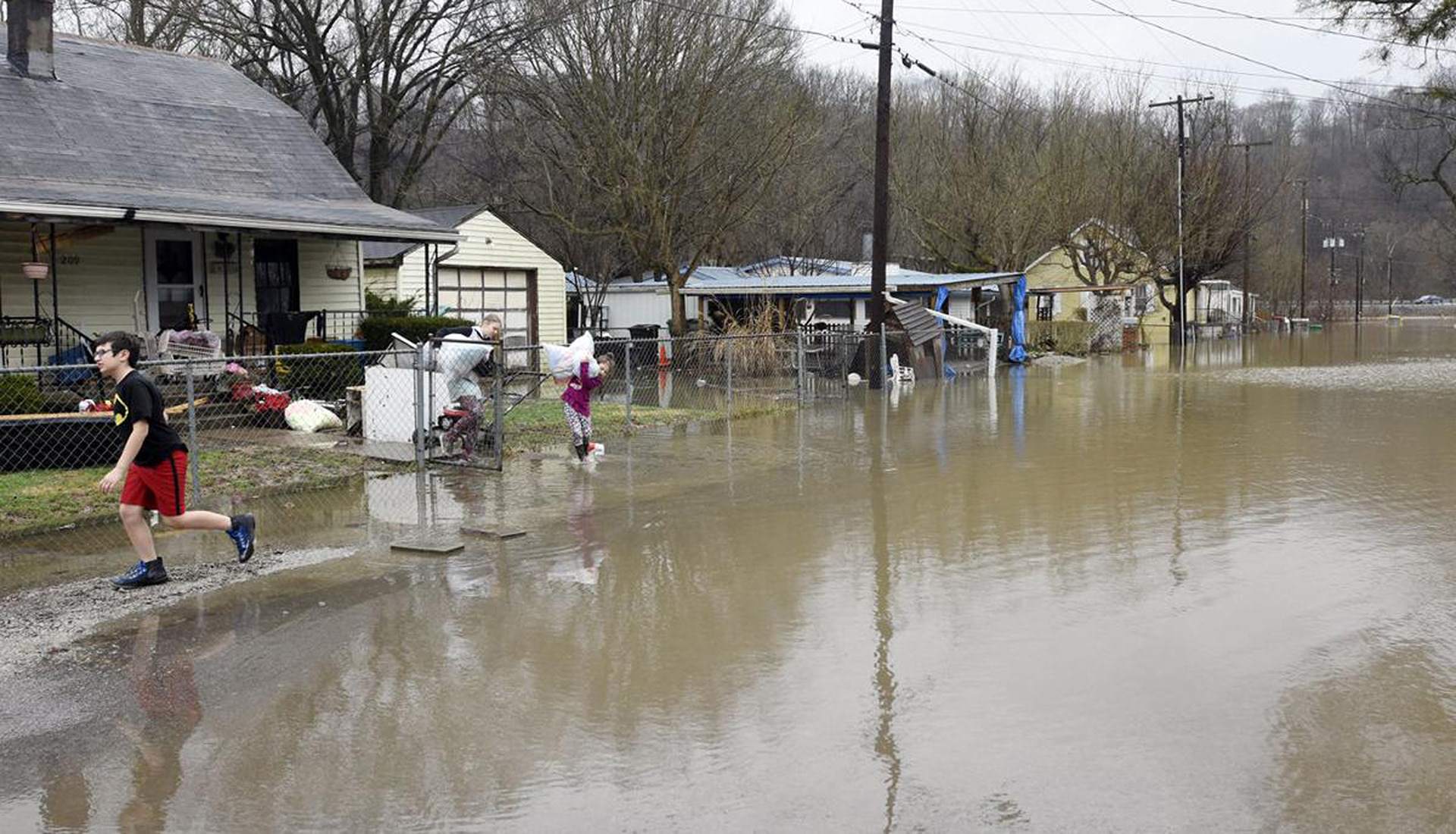 Children carry items from a home to a car Saturday, Feb. 24, 2018, as flood waters cover a section of 6th Street in West Point, Kentucky. (Jill Pickett/The News-Enterprise)