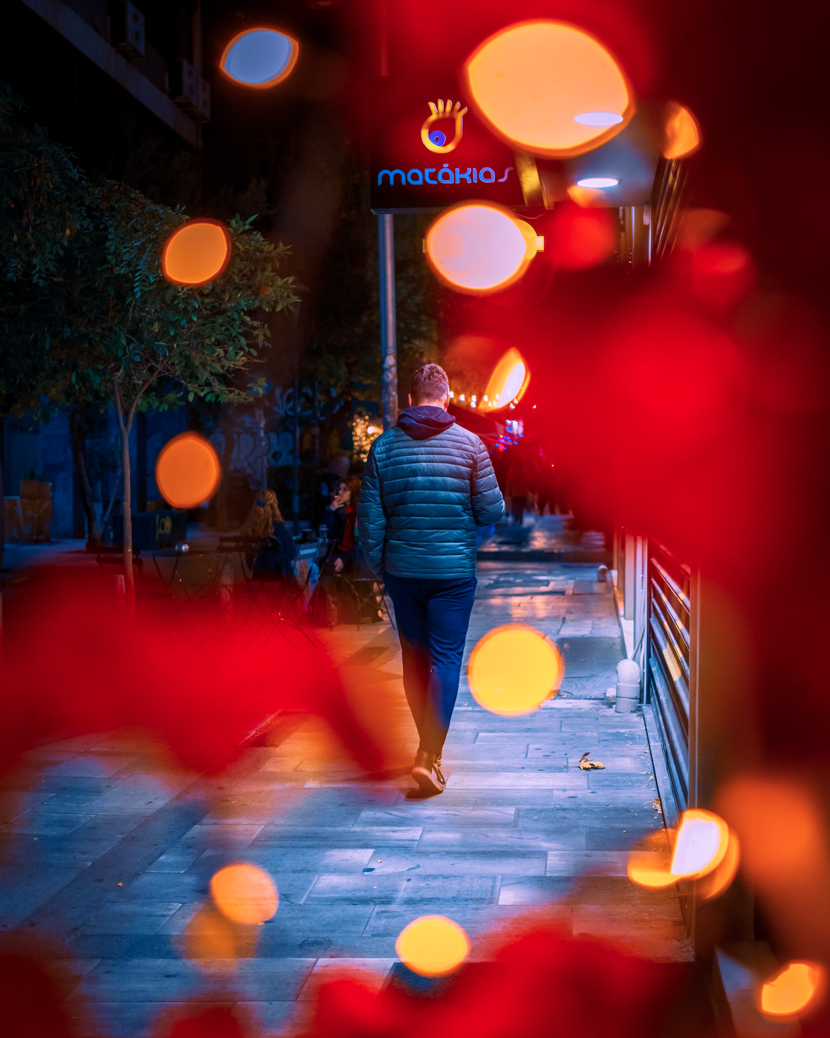 To me, photography is about finding the quiet center of the storm, especially as the city accelerates toward #ChristmasEve🎄 In this frame, the intense red glow of the #HolidayLights creates a cinematic veil, yet it is the cool hues that reveal the true character of my #SignatureBlue world. This is the essence of #GreekUrbanHiker 📸 A walk that ends up transforming an #Athens street into a living film set.
