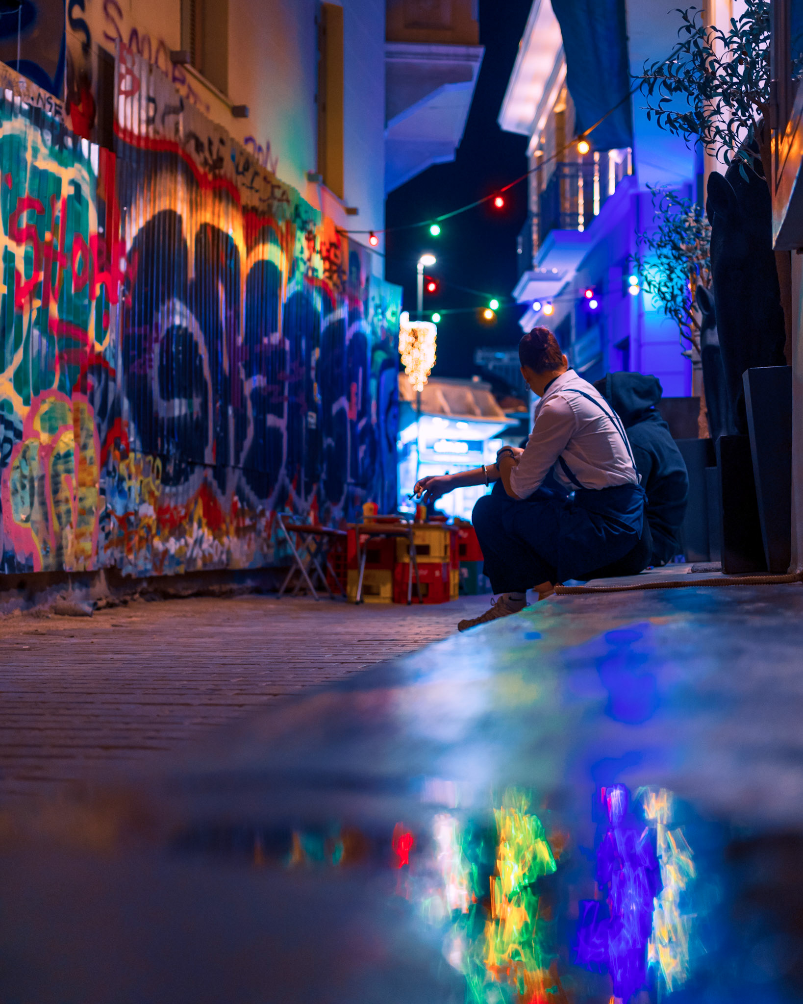 A moment in #Psirri, between two young ones 😊, having their break, on the #sidewalk, sharing thoughts, with the #reflections shining upon them 💎, and the #graffitis colouring 🖌️ the night!