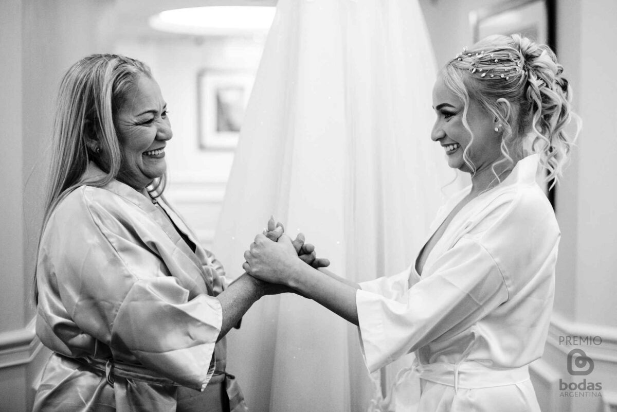 Novia y su madre tomadas de las manos riéndose durante los preparativos — fotografía documental de bodas Buenos Aires, Anto Ventimiglia