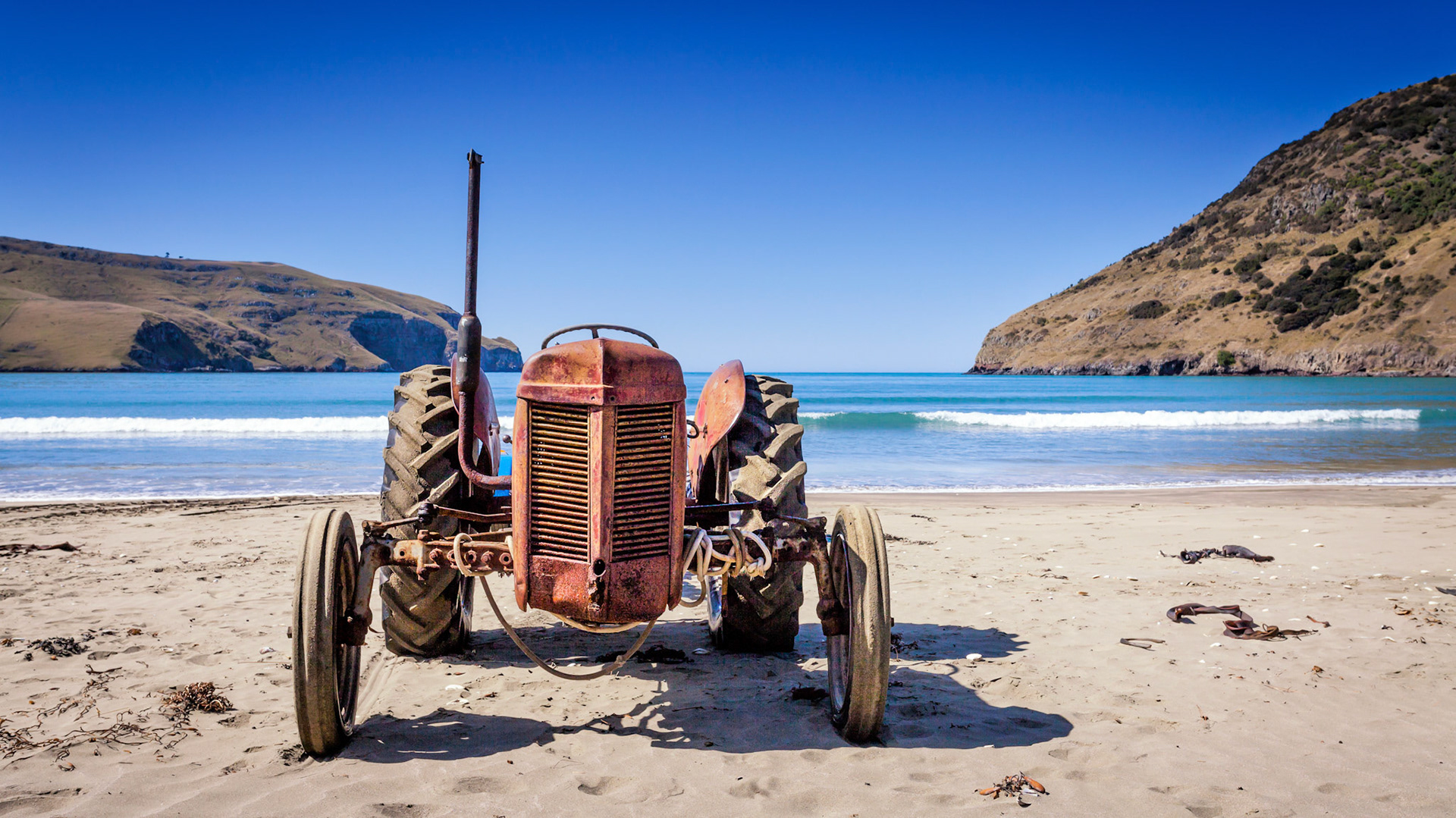 A red tractor on the beach at Le Bond Bay, Banks Peninsula