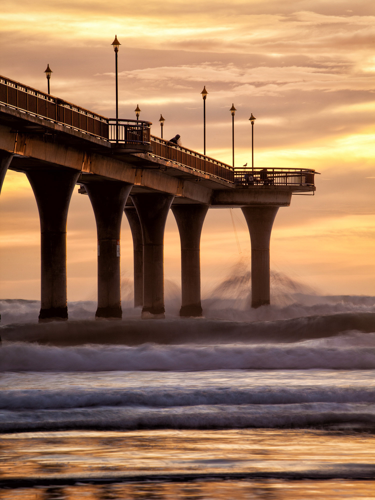 Soft afternoon light highlighting waves crashing into New Brighton Pier, Christchurch
