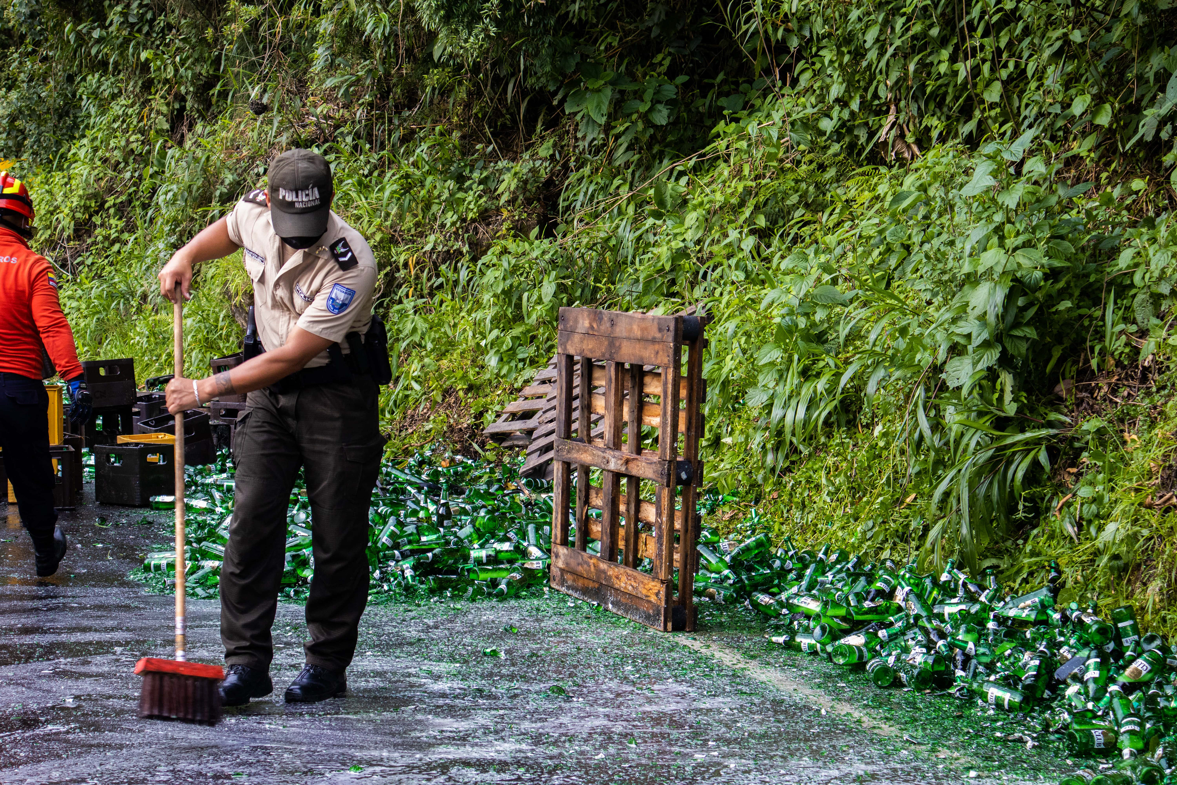 Police officer sweeping beer bottles.