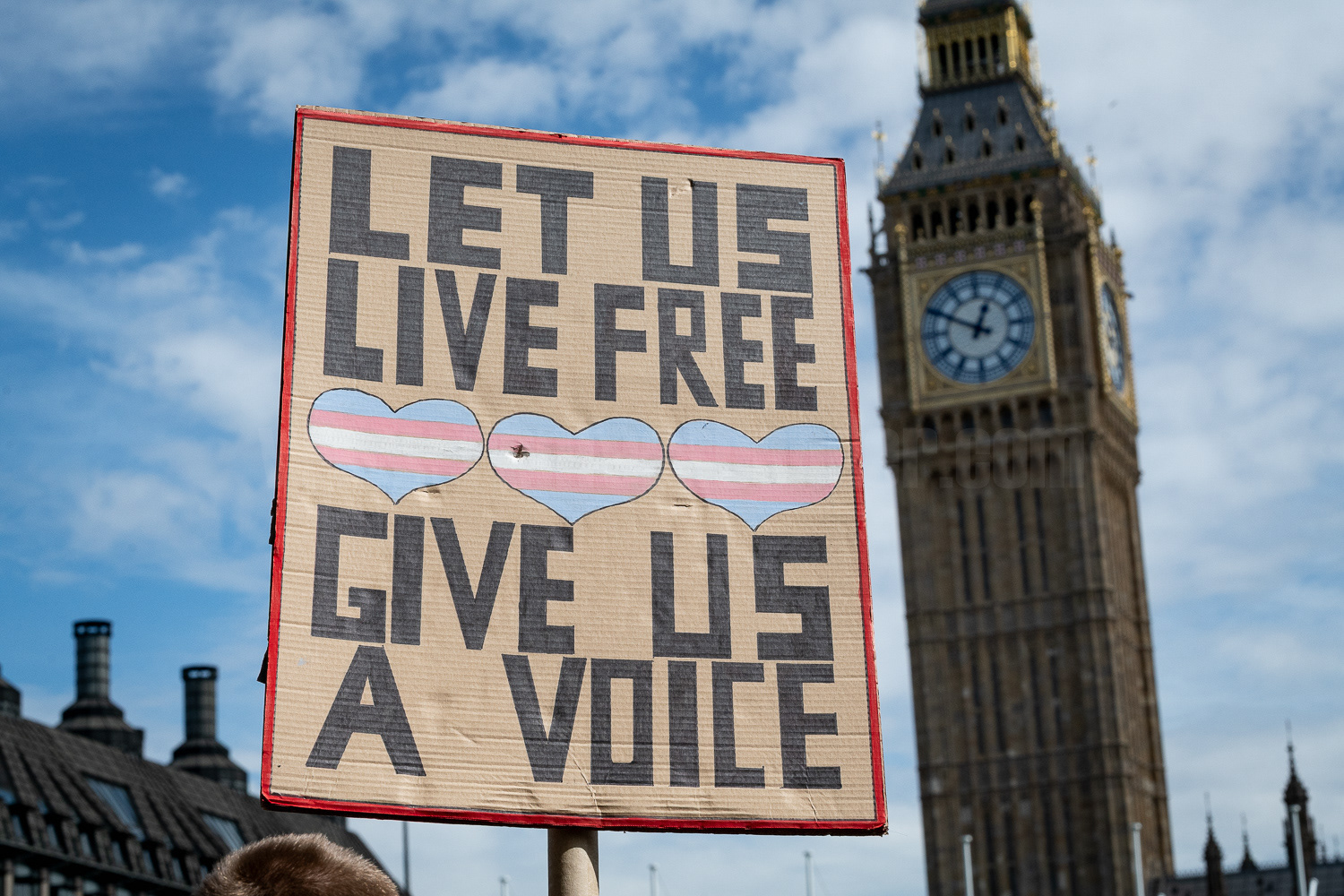 A placard is held aloft during a transgender rights protest in Parliament Square, London, with Big Ben in the background.