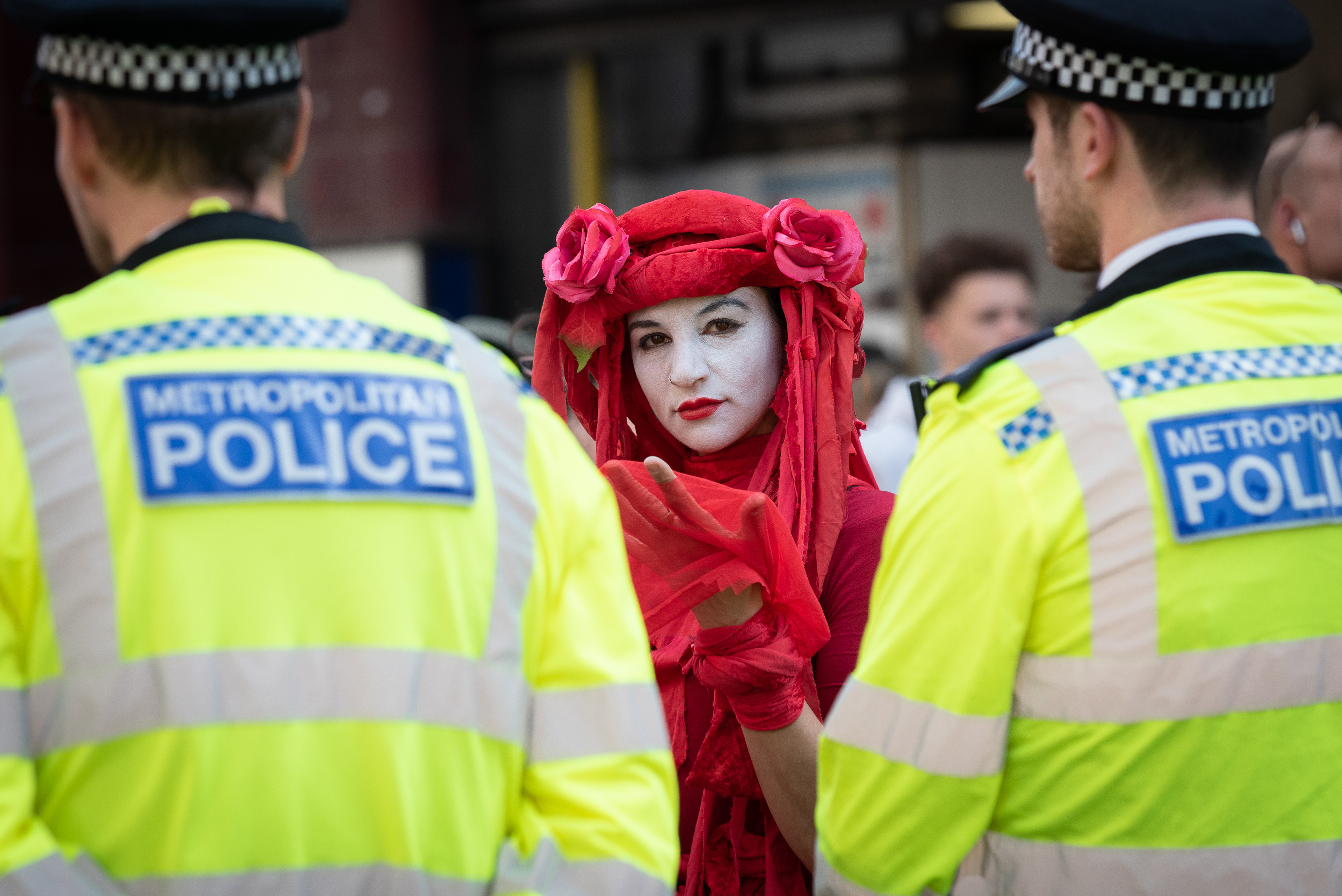 Red Rebel looks in to a police cordon surrounding locked-on activists in Oxford Circus. © Ron Fassbender