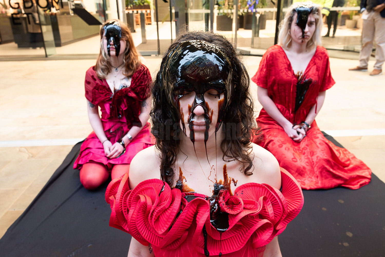 Climate activists covered in fake oil outside London HQ of oil company Equinor