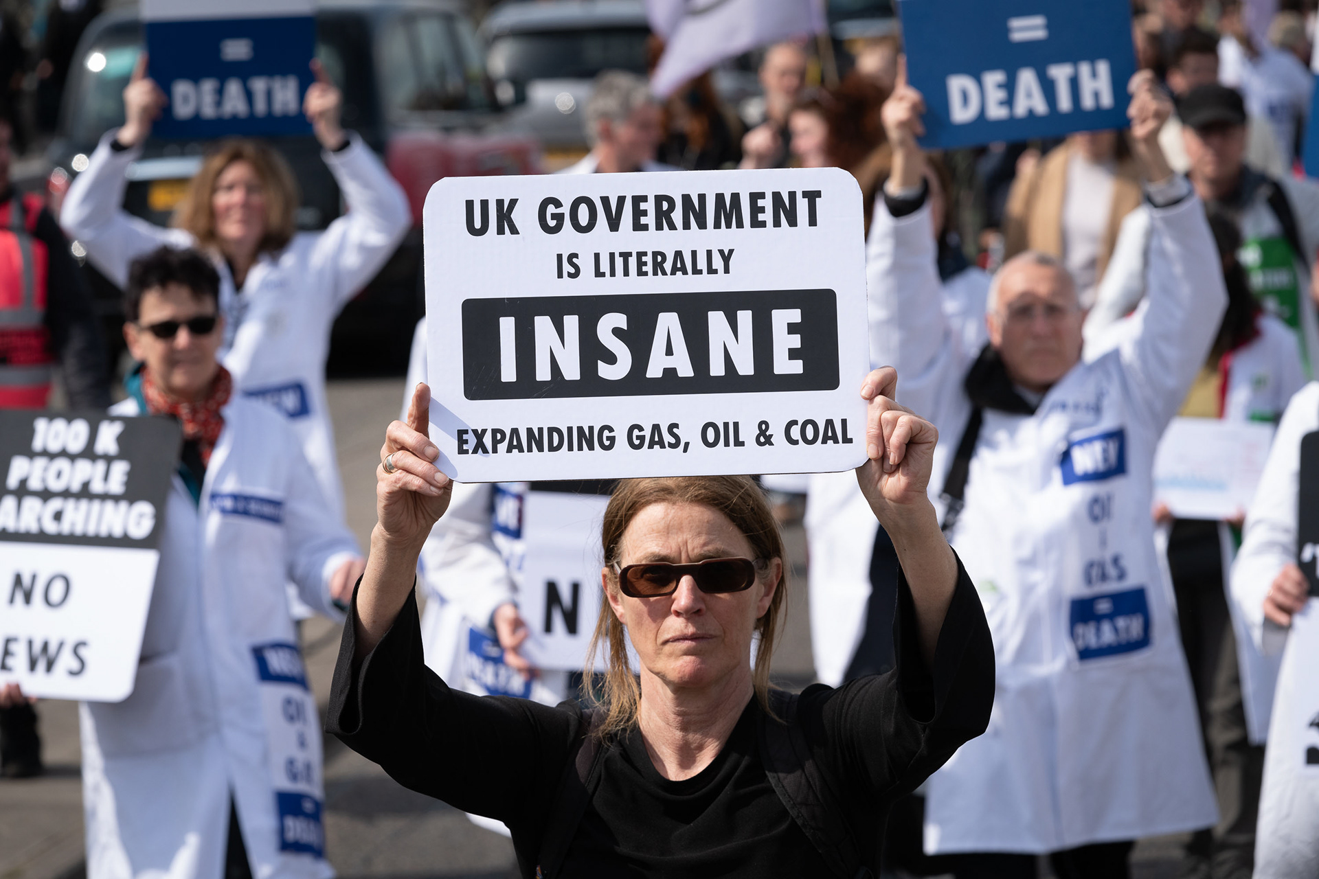 Scientists march across London Bridge carrying placards warning of government actions worsening global heating